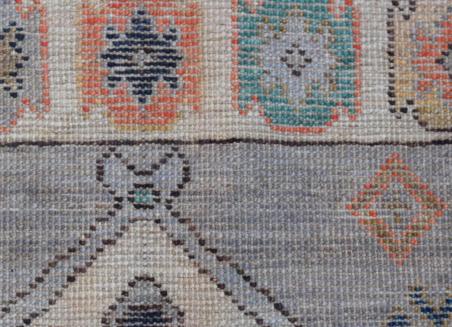 A handwoven transitional Oushak rug featuring geometric patterns in muted tones on wool.