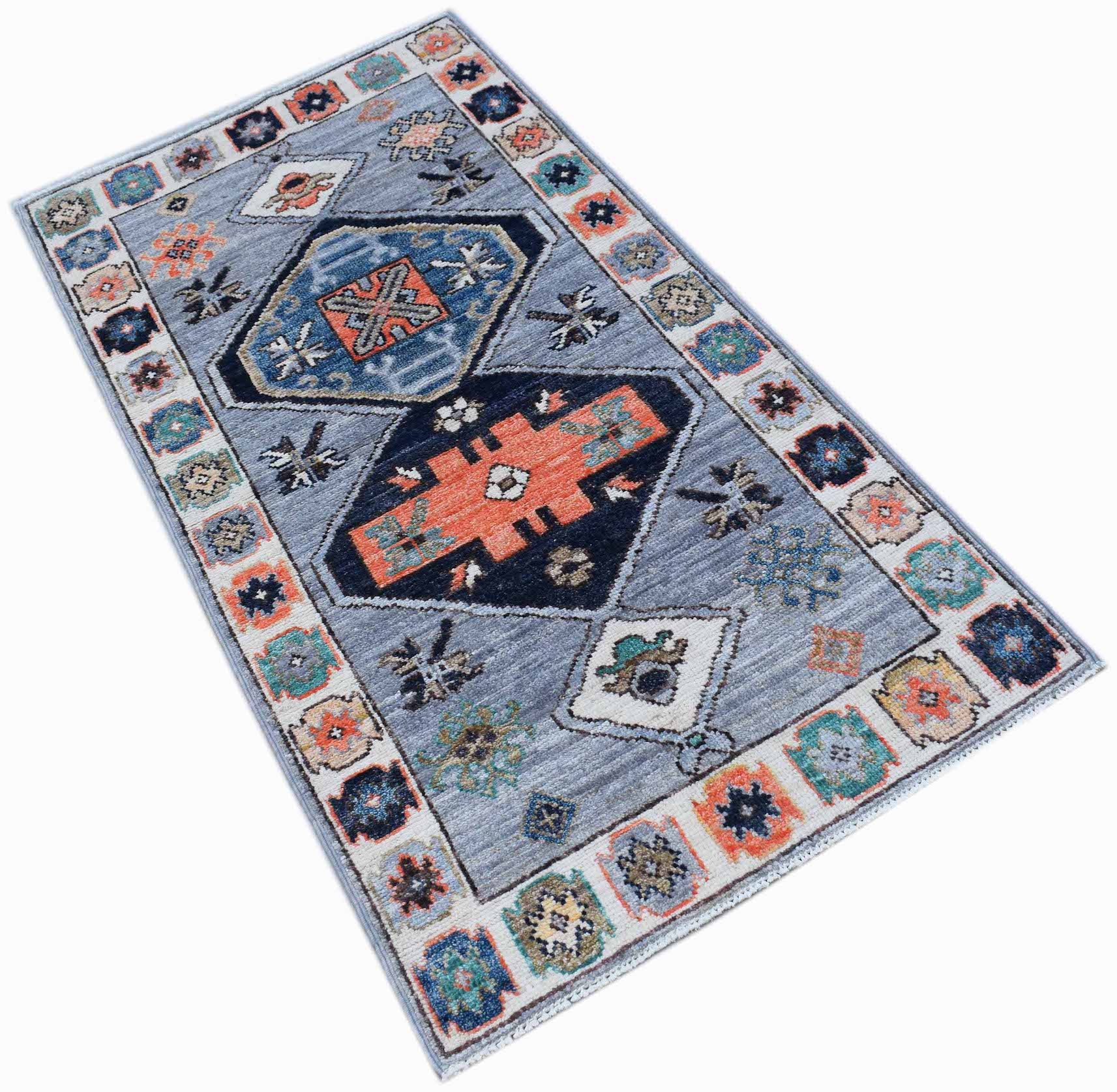 A handwoven transitional Oushak rug featuring a geometric pattern in blue, orange, and cream.