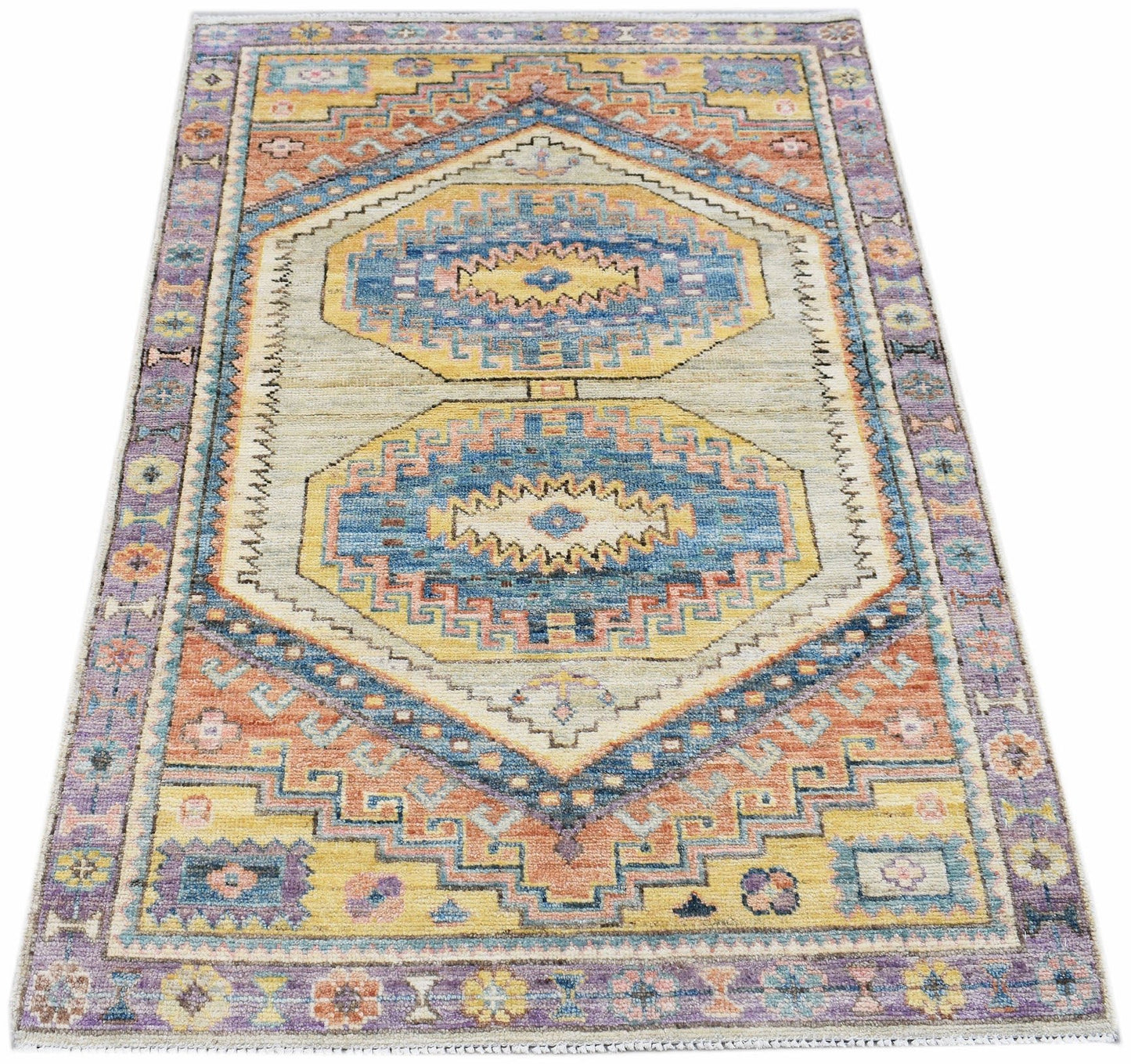 A handwoven transitional Oushak rug featuring a geometric pattern in blue, yellow, and orange.