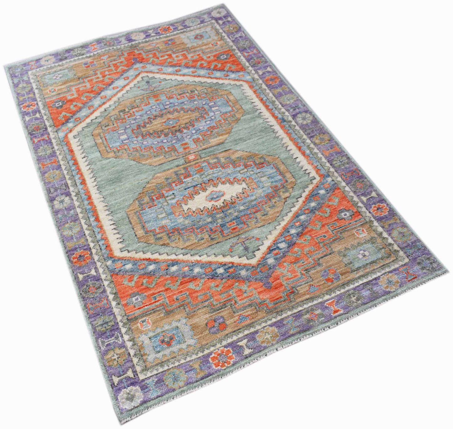 A handwoven transitional Oushak rug featuring geometric patterns in blue, orange, and purple tones.