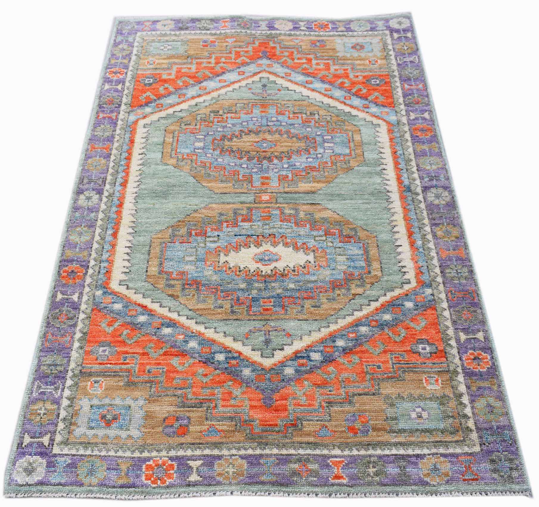 A handwoven transitional Oushak rug featuring geometric patterns in blue, orange, and purple tones.