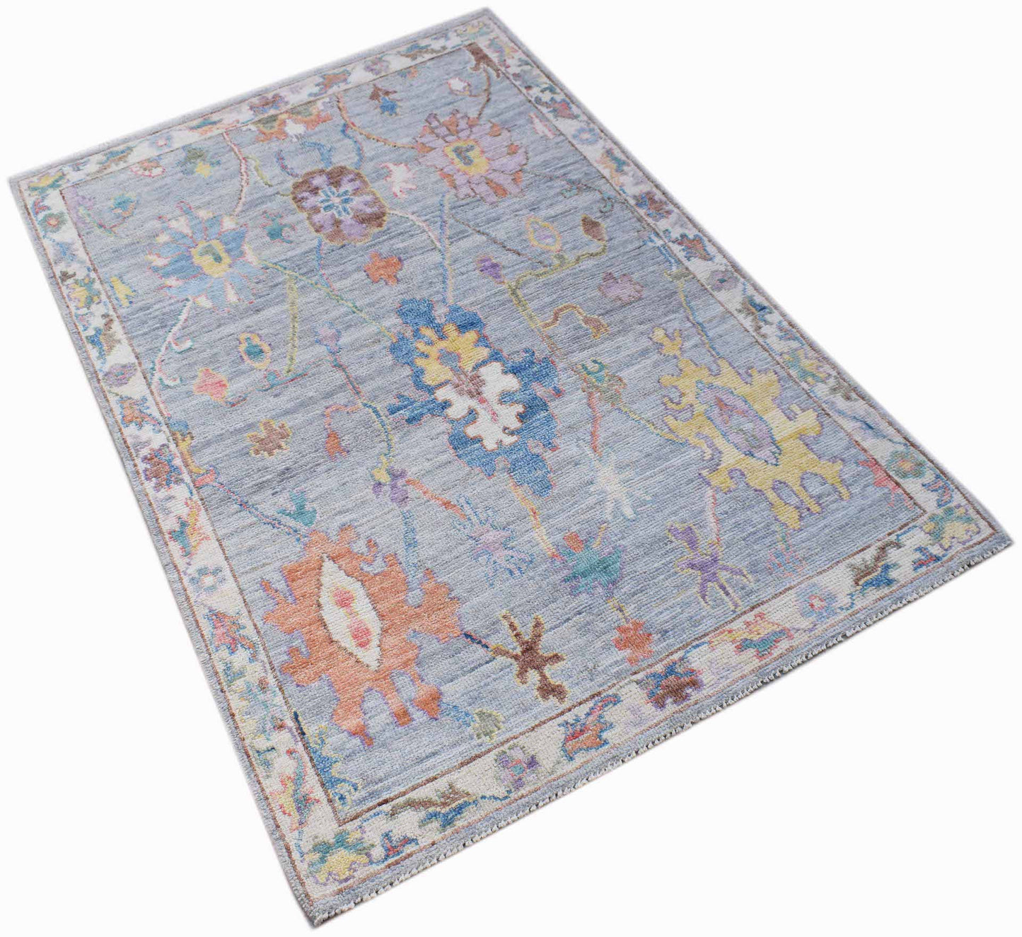 A handwoven transitional Oushak rug featuring a floral pattern in soft blue and multi-colored tones.