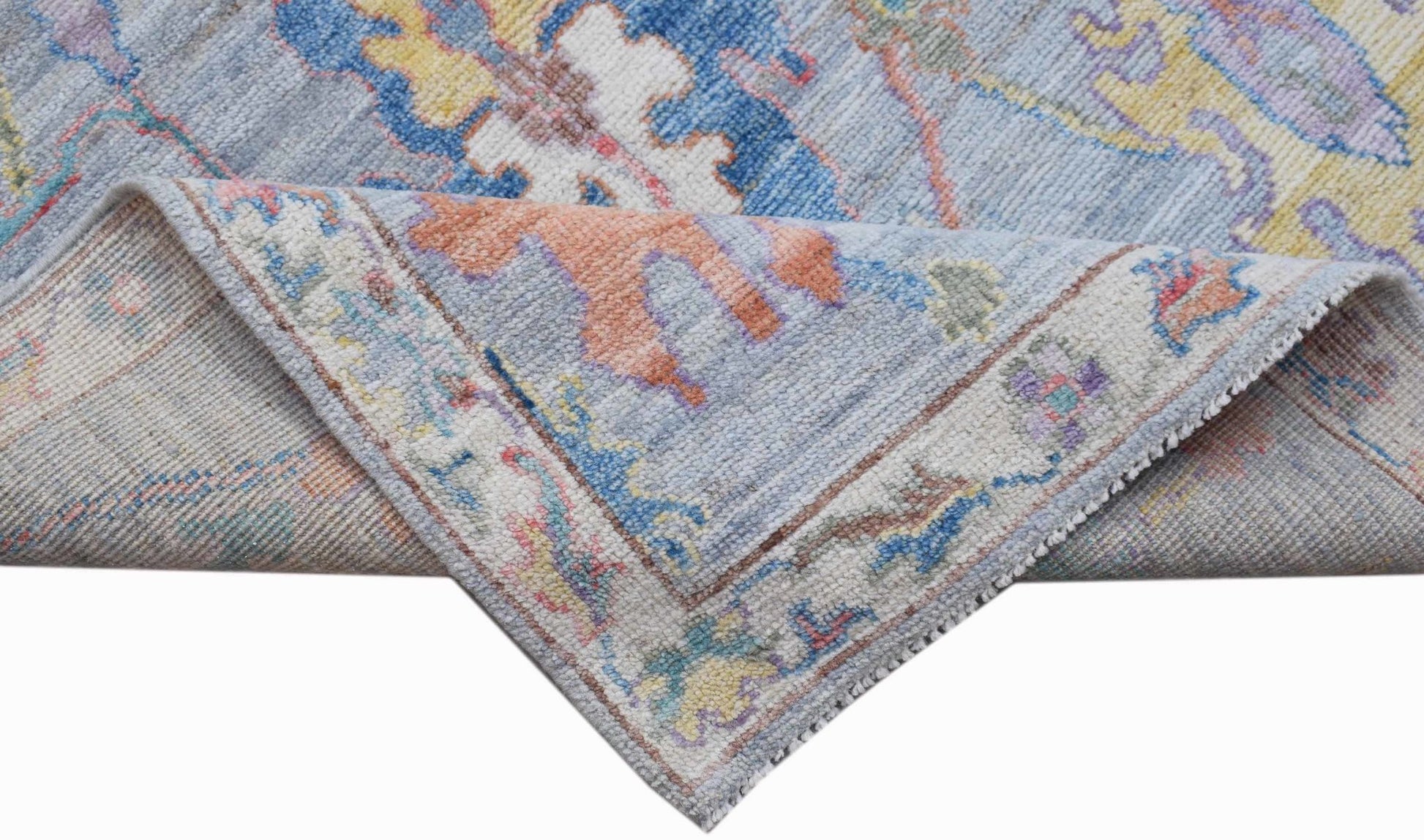 A handwoven transitional Oushak rug featuring a floral pattern in soft blue and pastel tones.