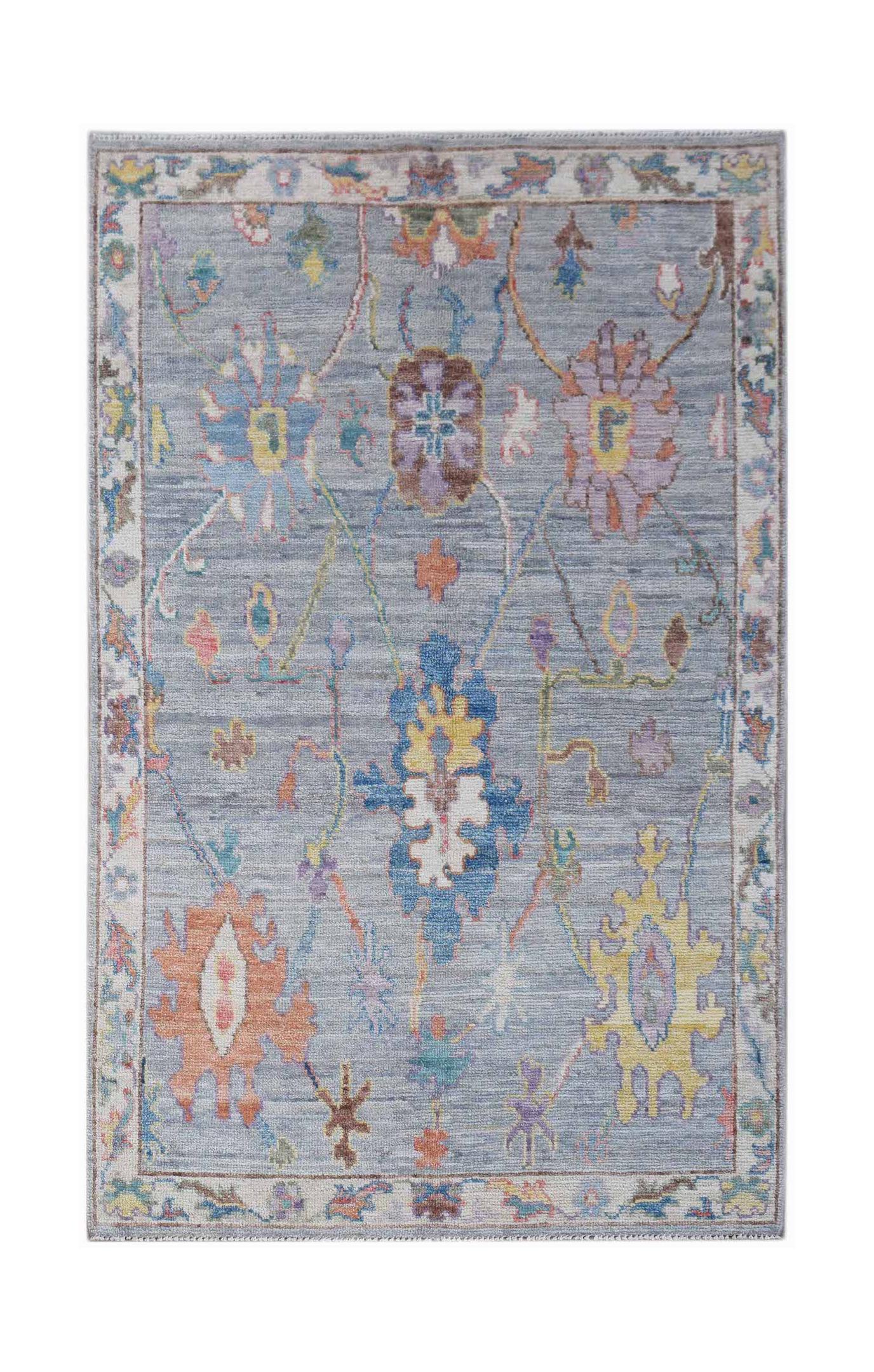 A handwoven transitional Oushak rug featuring a floral pattern in colorful tones on a grey field.