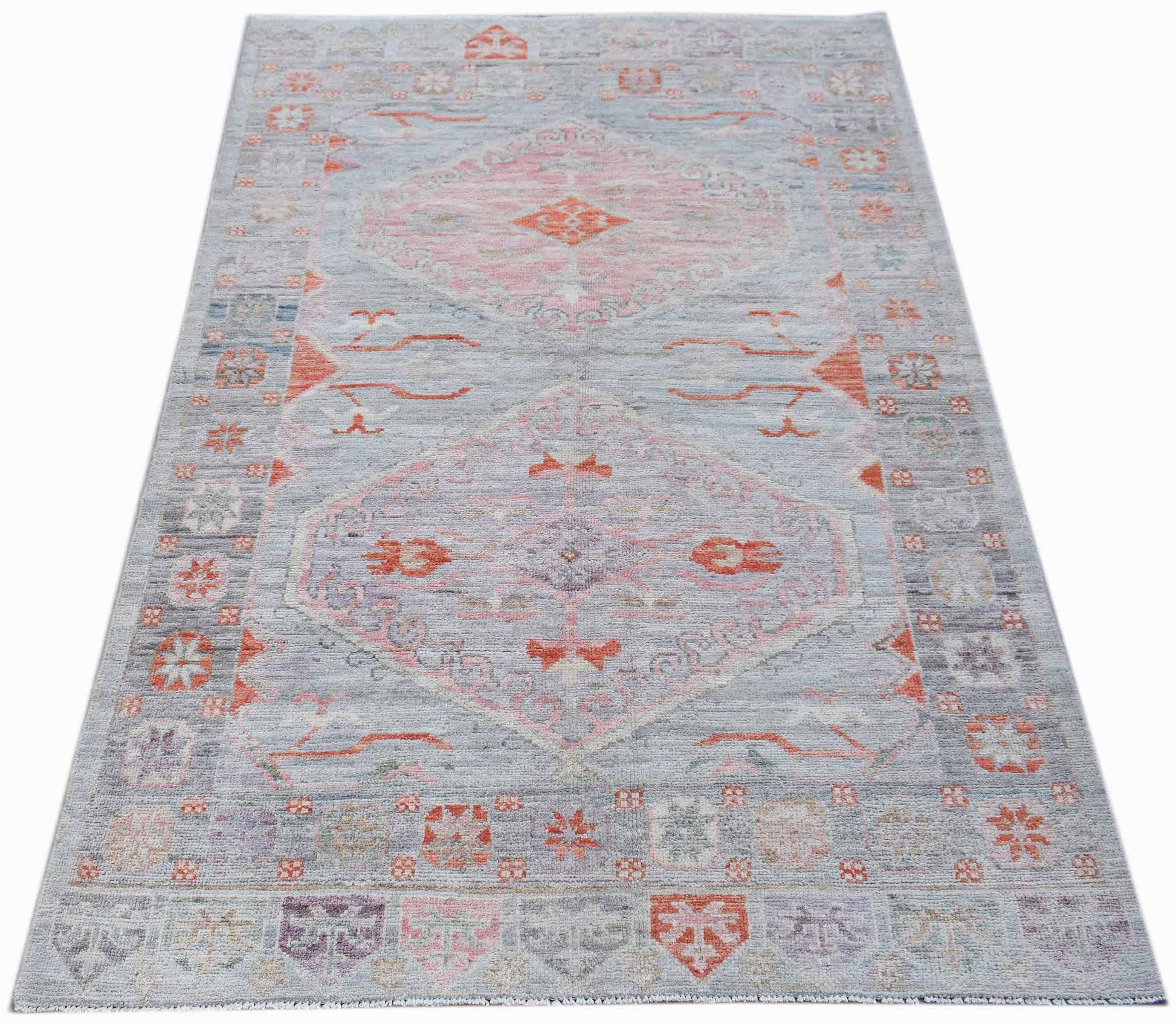 A handwoven transitional Oushak rug featuring a light blue background with pink and orange motifs.