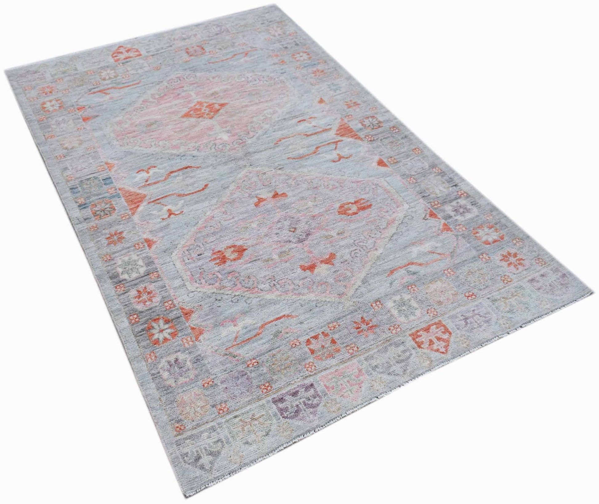 A handwoven transitional Oushak rug featuring a light blue field with pink and orange floral motifs.