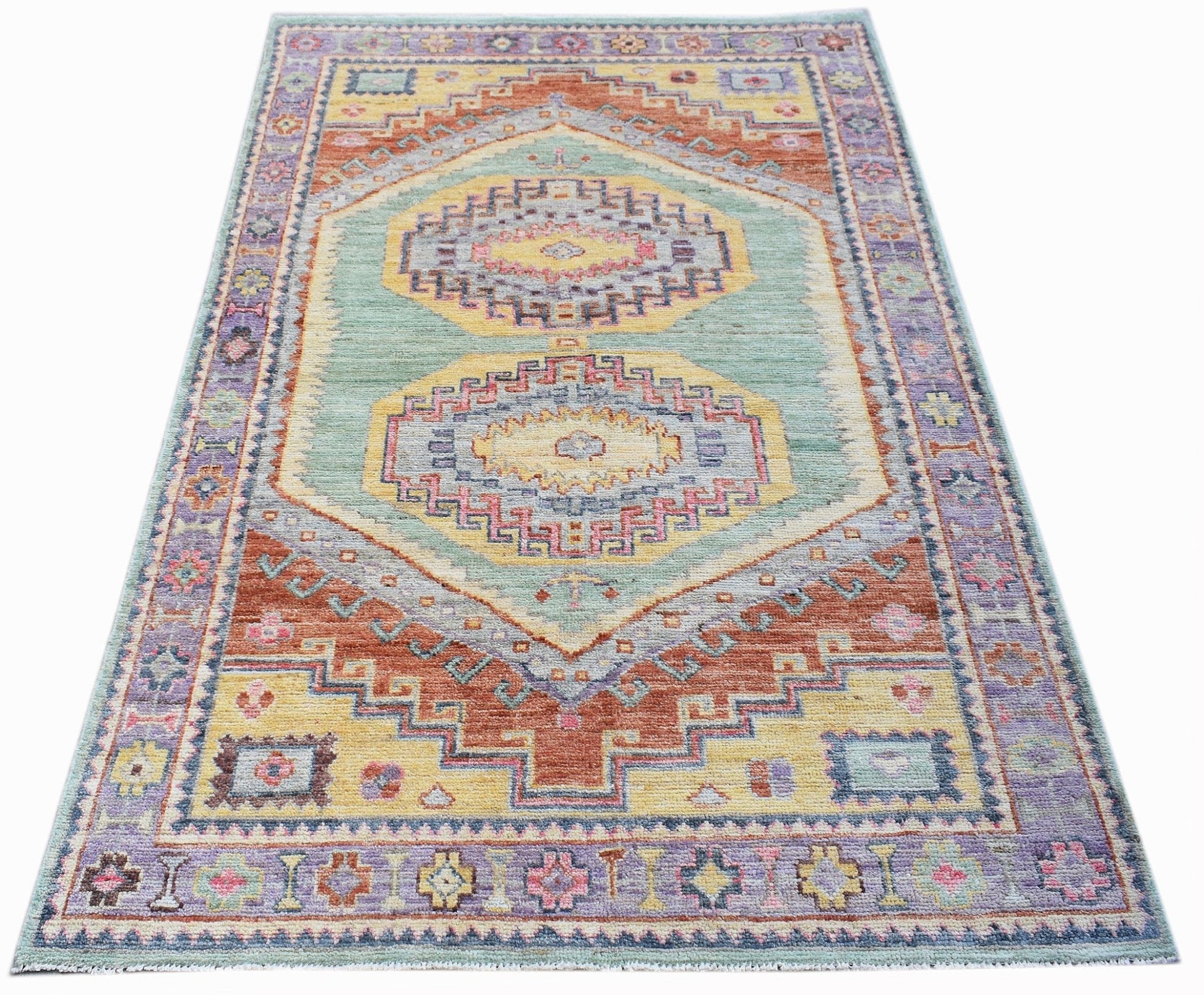 A handwoven transitional Oushak rug featuring geometric patterns in soft blue, yellow, and rust.