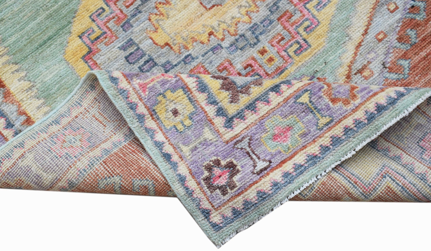 A handwoven transitional Oushak rug featuring a colorful geometric pattern on wool.