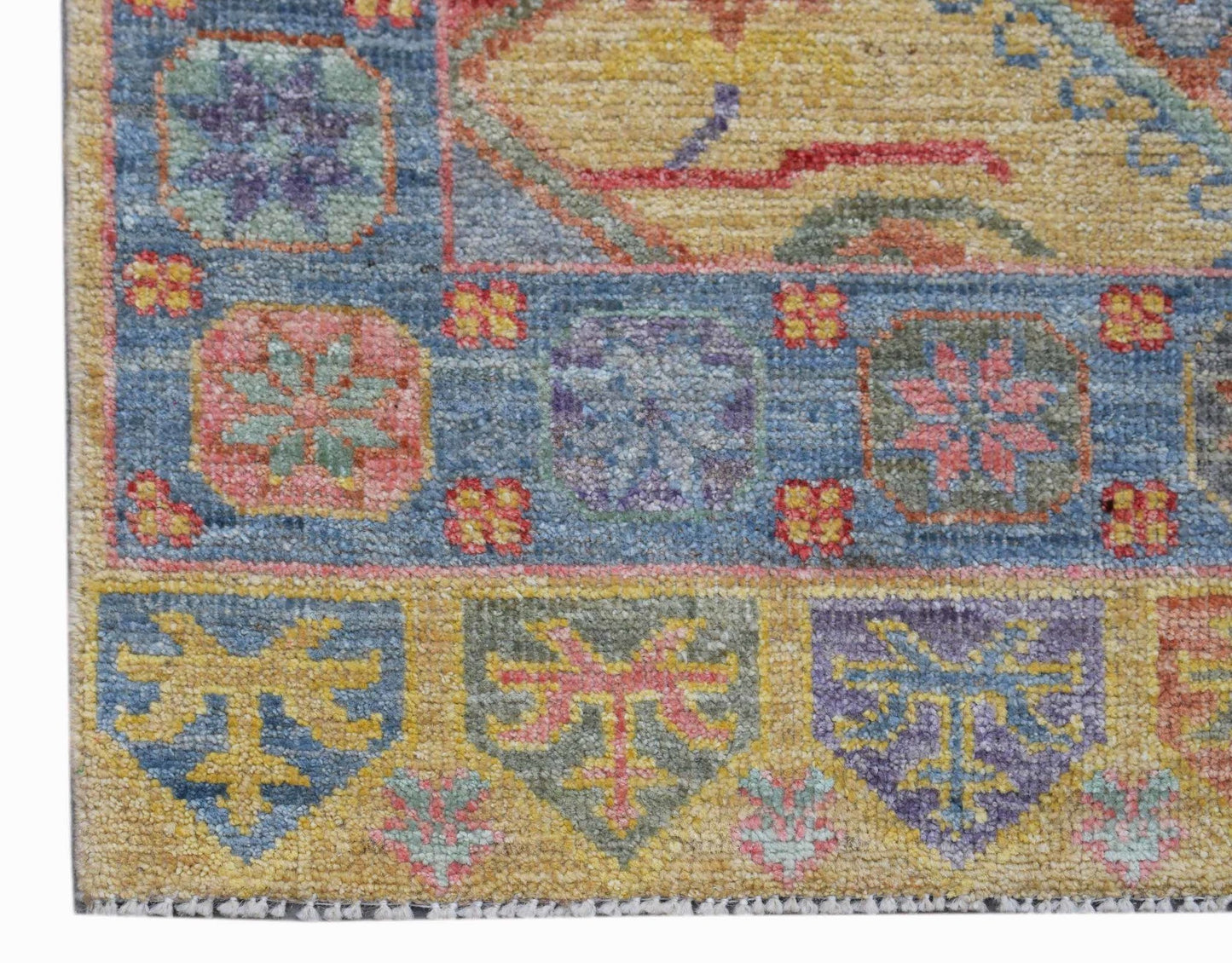 A handwoven transitional Oushak rug featuring a colorful floral pattern on a yellow background.