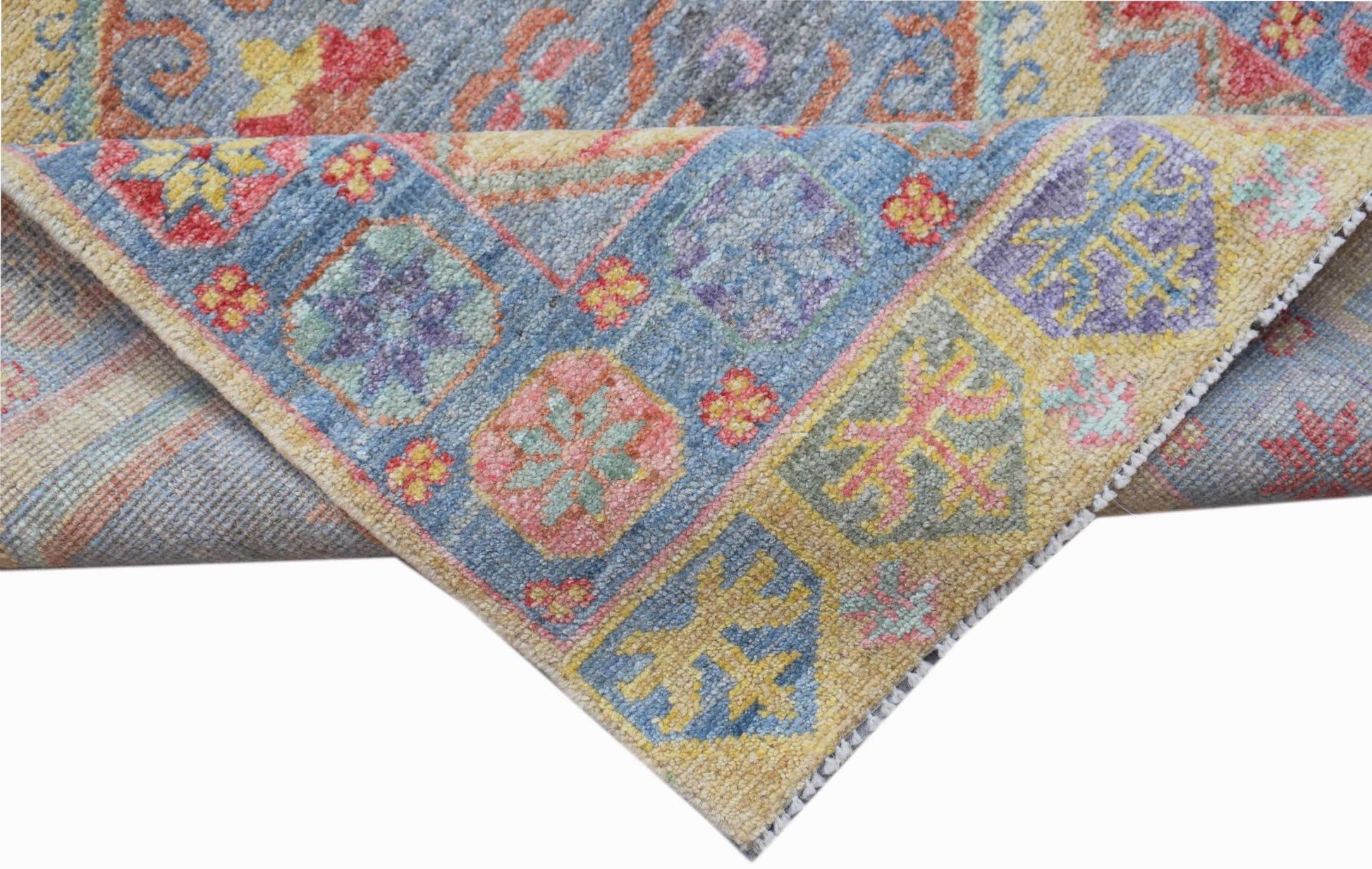 A handwoven transitional Oushak rug featuring a colorful floral pattern on a blue and yellow field.
