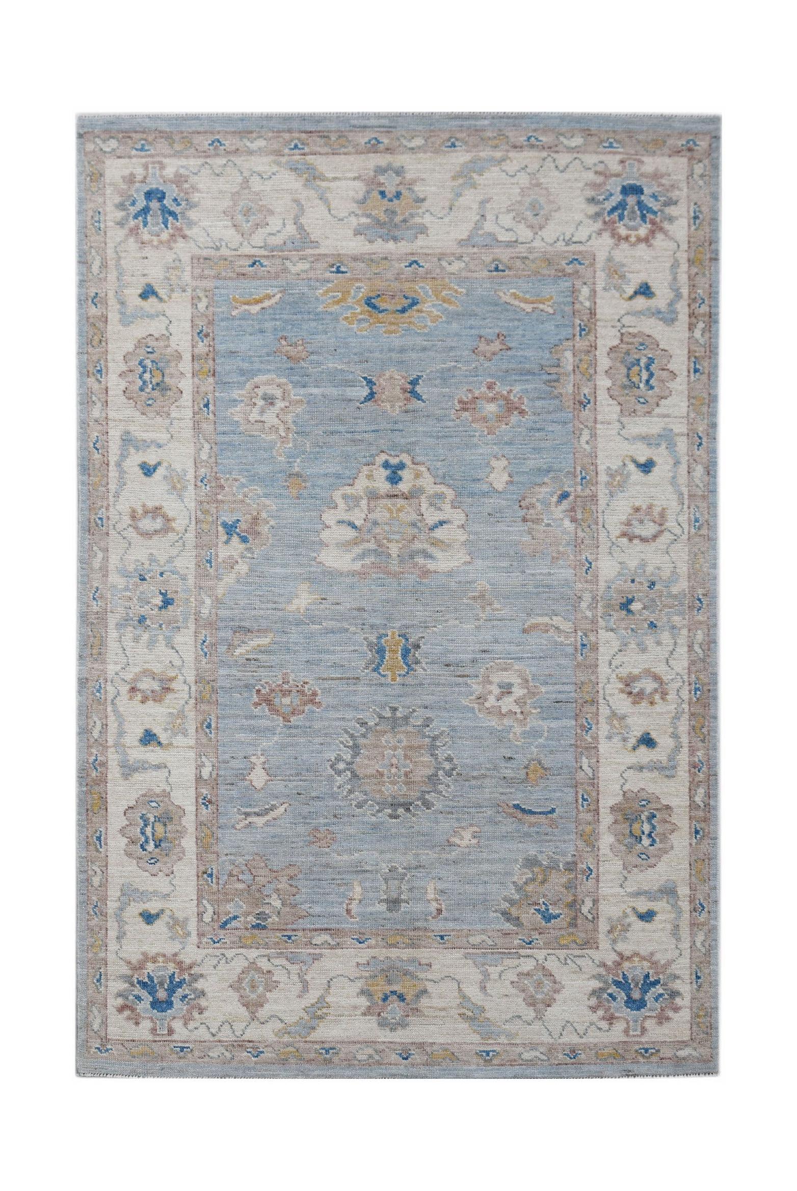 A handwoven transitional Oushak rug featuring a floral pattern in blue, beige, and grey tones.