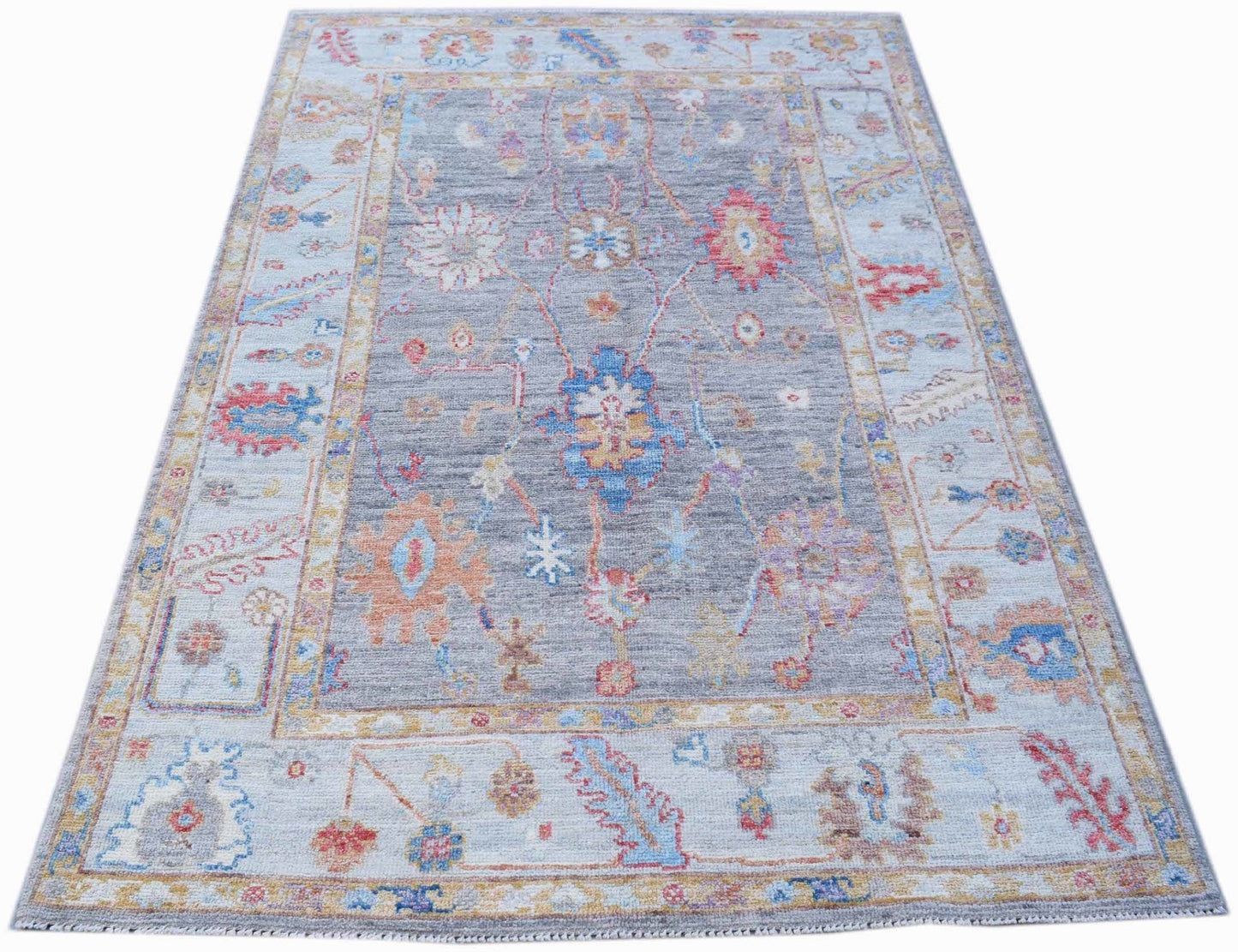A handwoven transitional Oushak rug featuring a floral pattern in blue, orange, and grey tones.