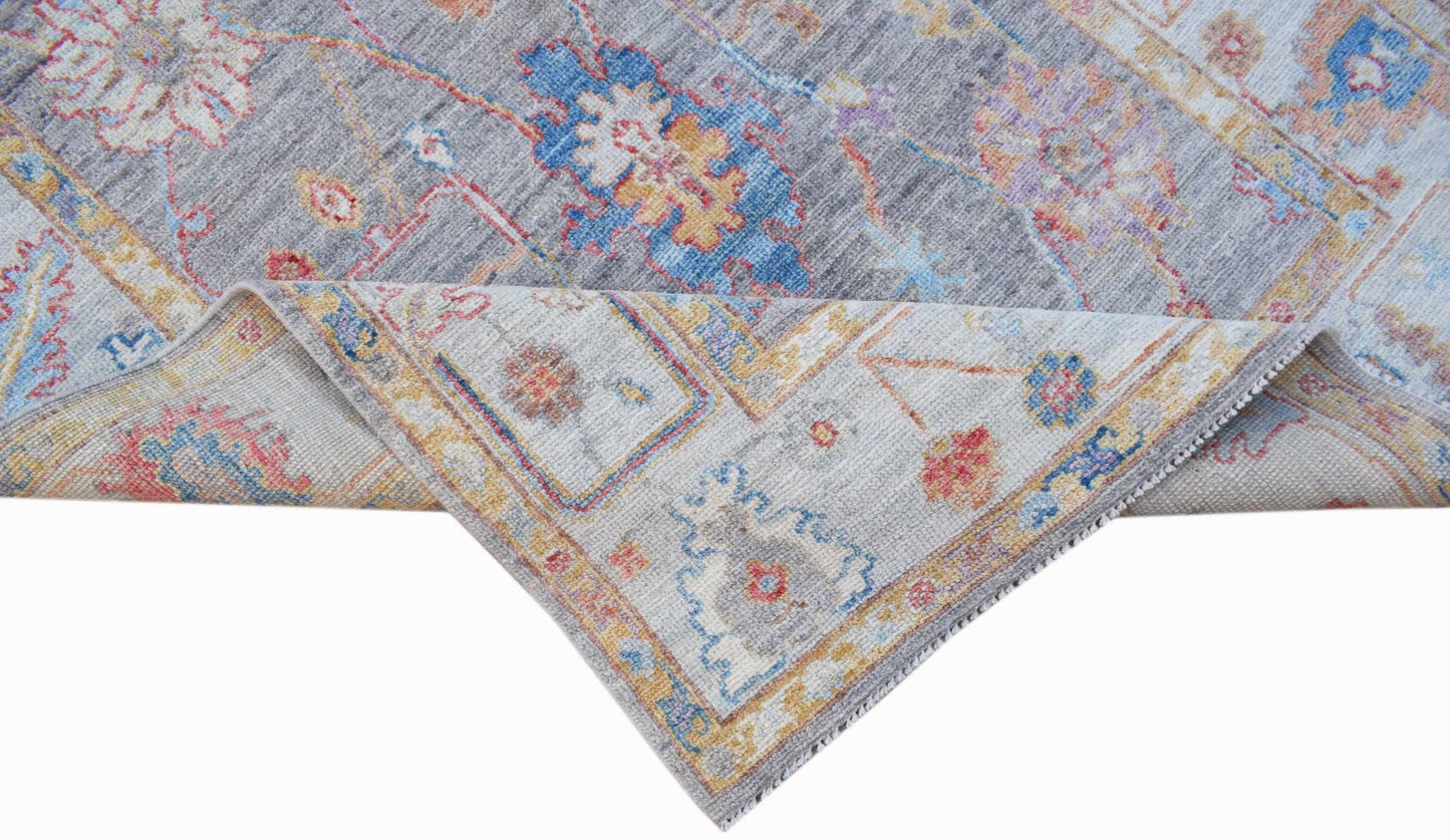 A handwoven transitional Oushak rug featuring a floral pattern in blue, grey, and muted tones.