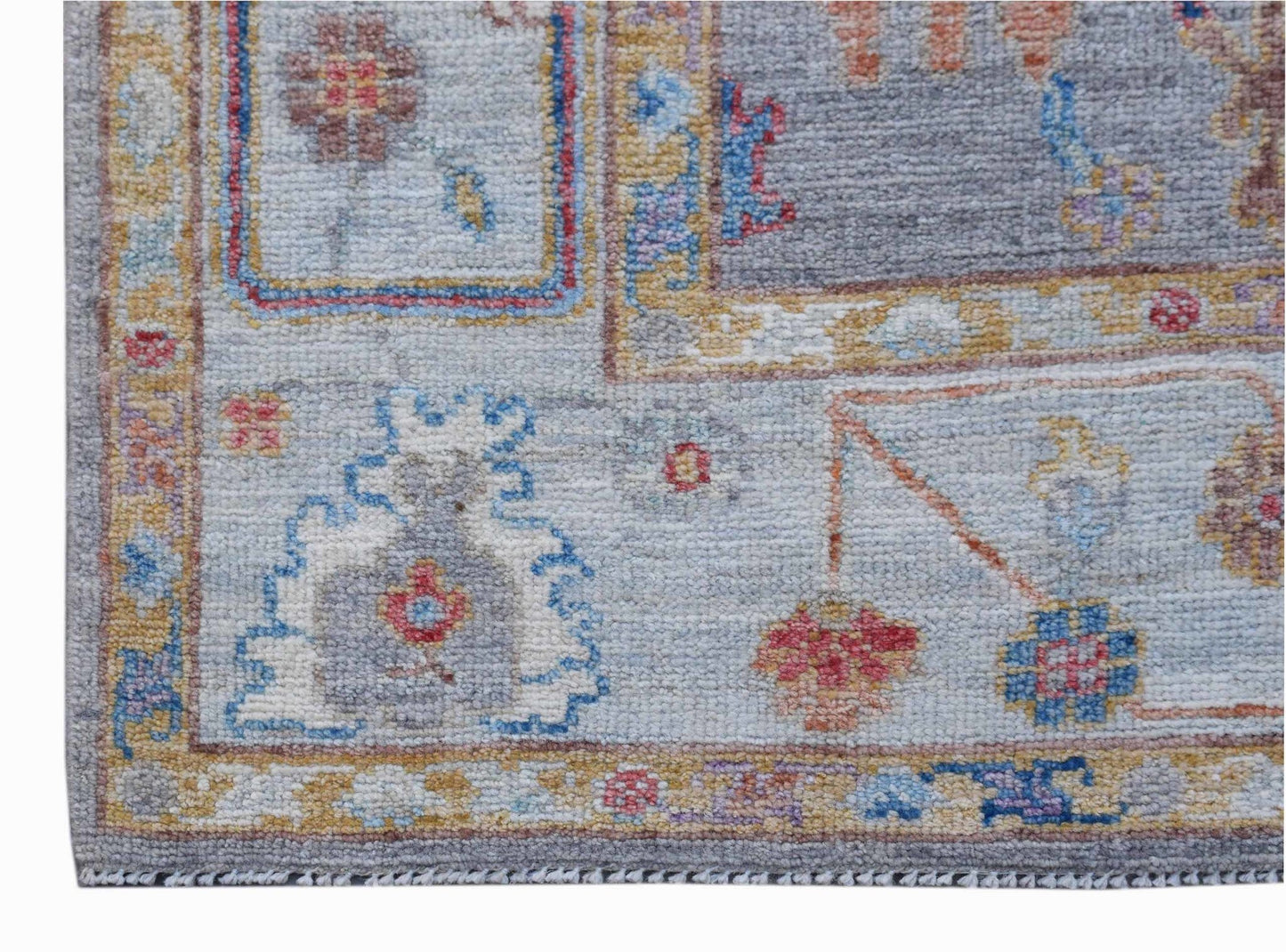A handwoven transitional Oushak rug featuring a floral pattern in soft blue and neutral tones.