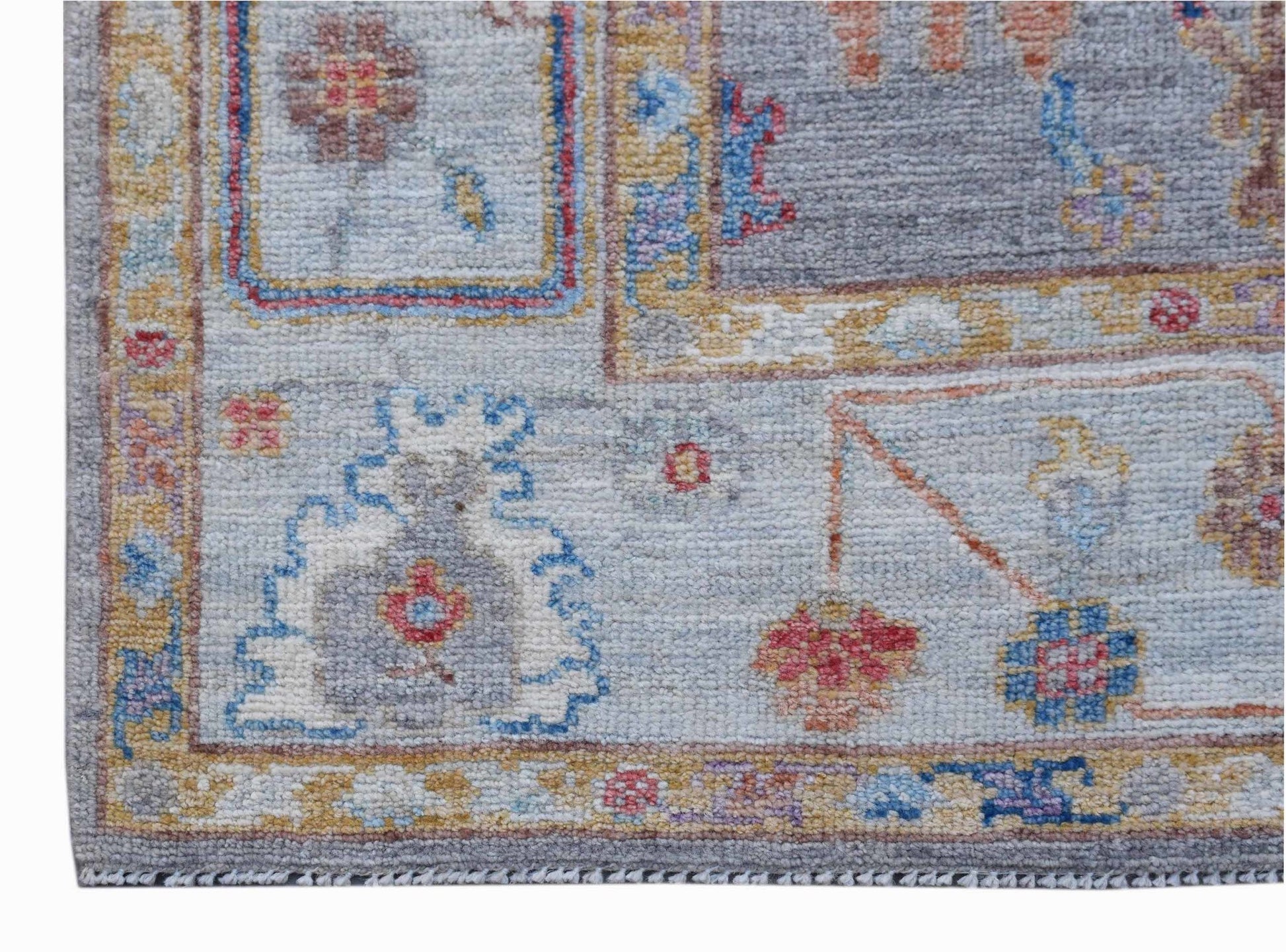 A handwoven transitional Oushak rug featuring a floral pattern in soft blue and neutral tones.