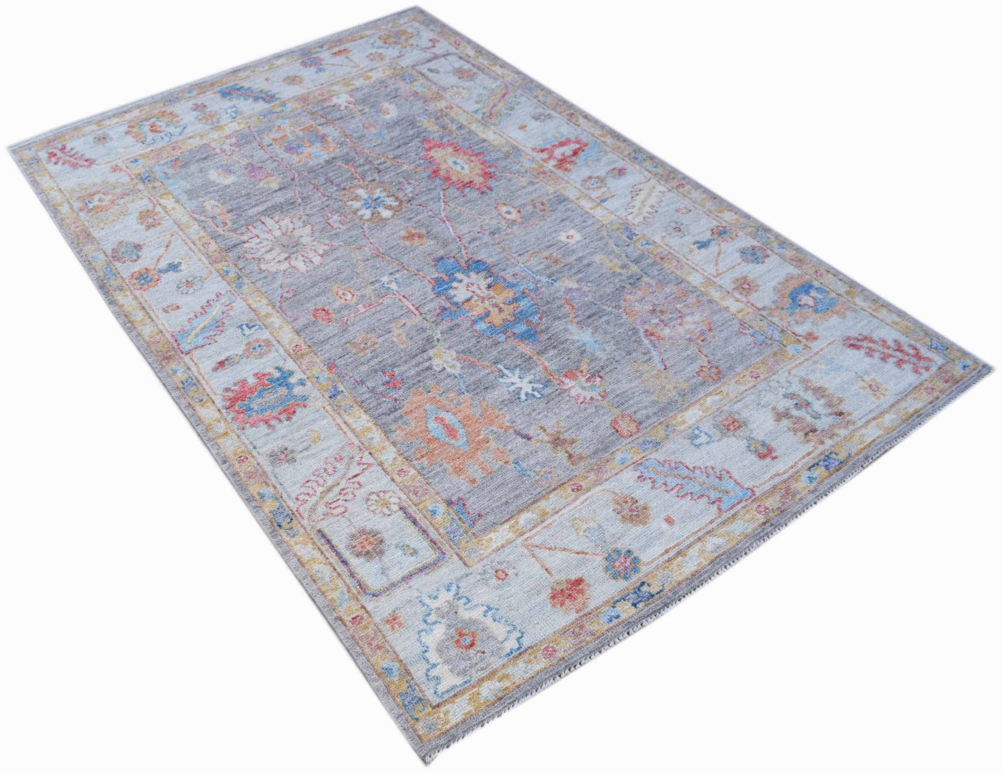 A handwoven transitional Oushak rug featuring a floral pattern in muted tones on a grey background.