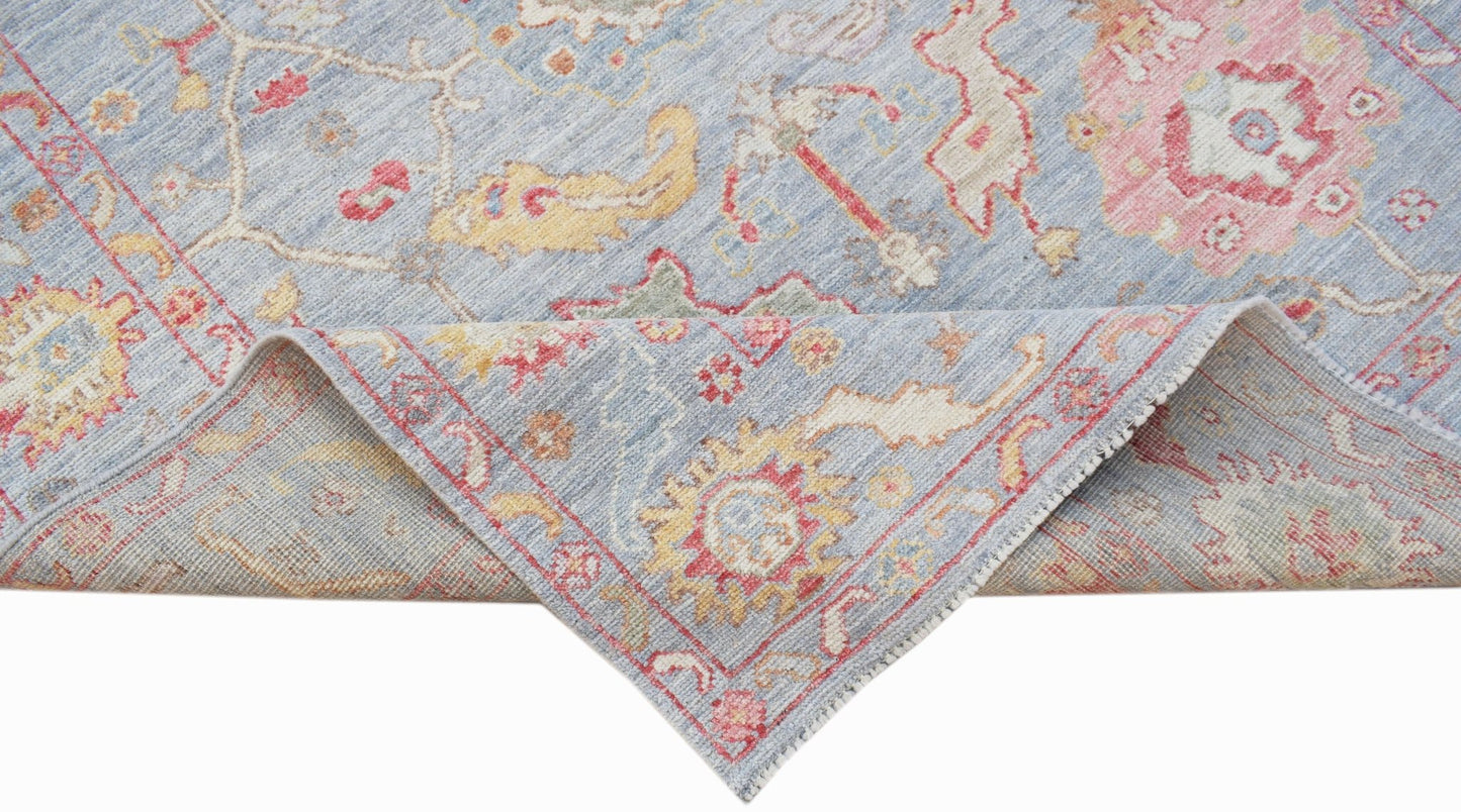 A handwoven transitional Oushak rug in light blue with floral patterns in pink and yellow.