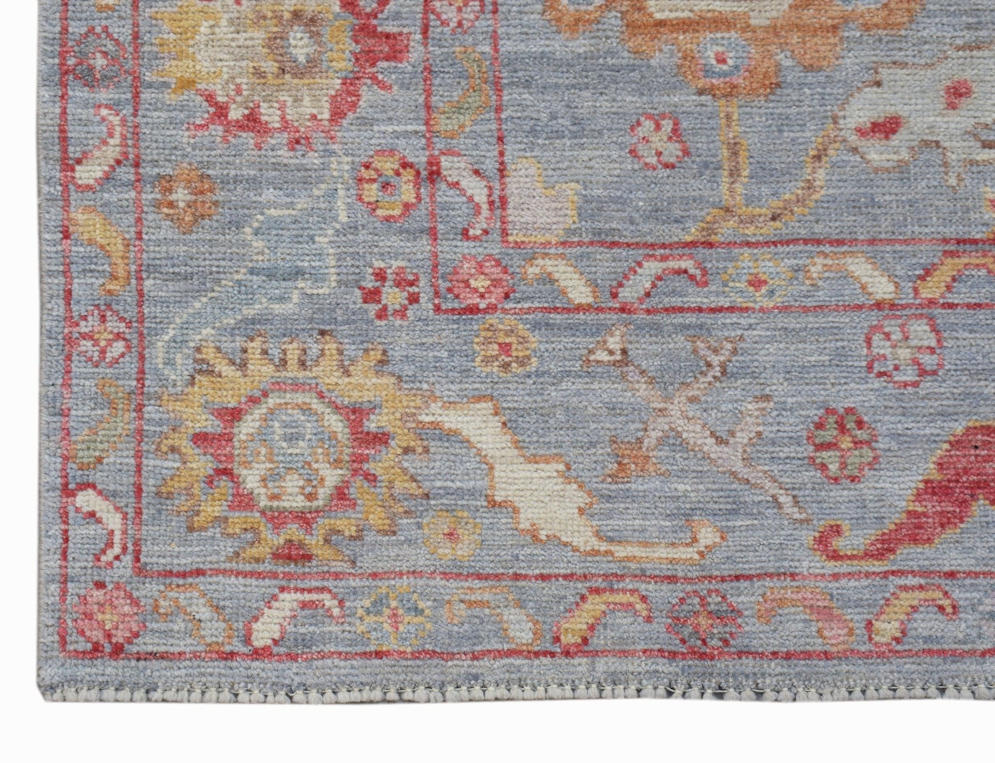 A transitional Oushak rug featuring a floral pattern in red, yellow, and blue on a grey background.