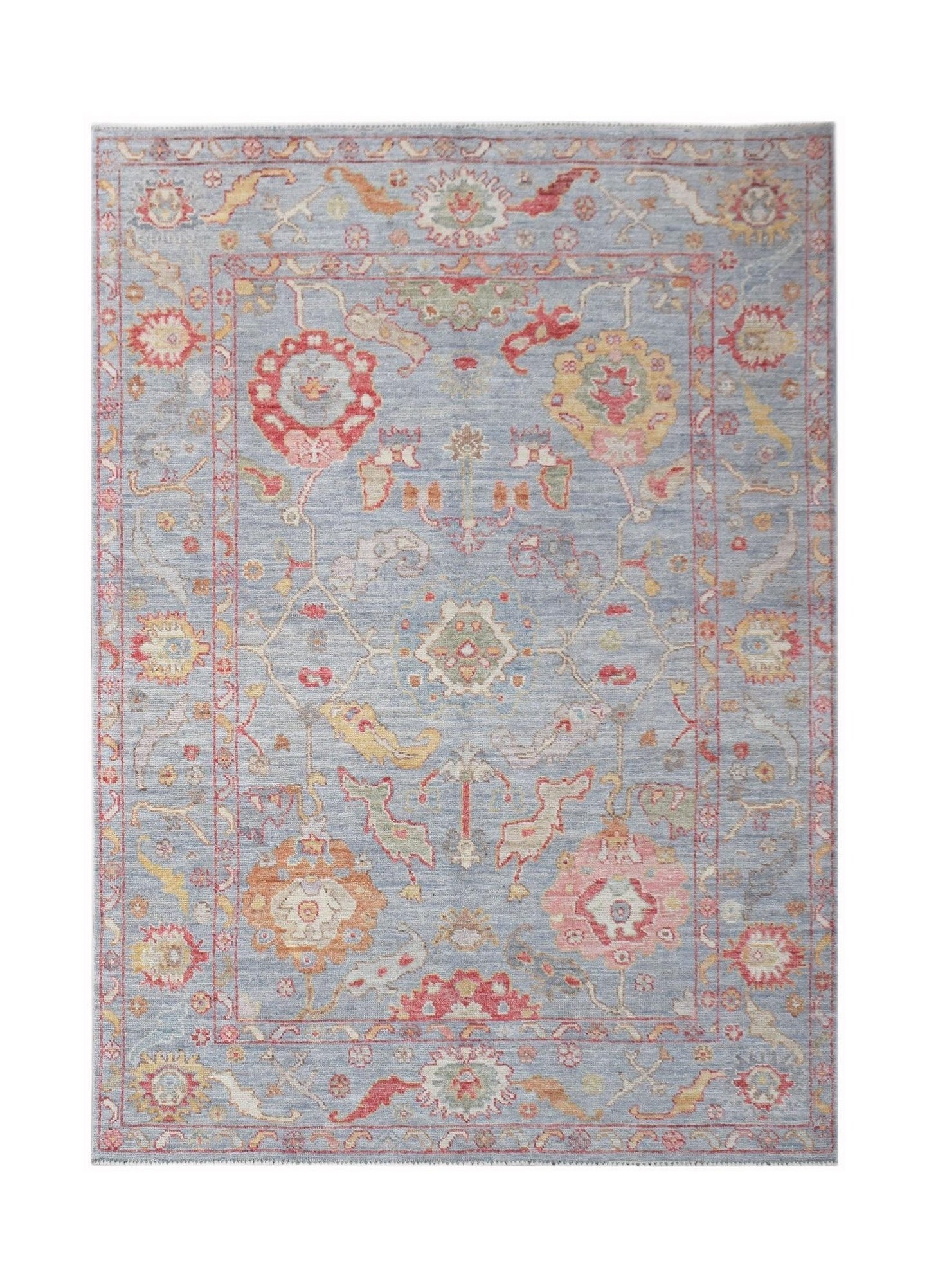 A handwoven transitional Oushak rug featuring a floral pattern in soft blue, red, and yellow tones.