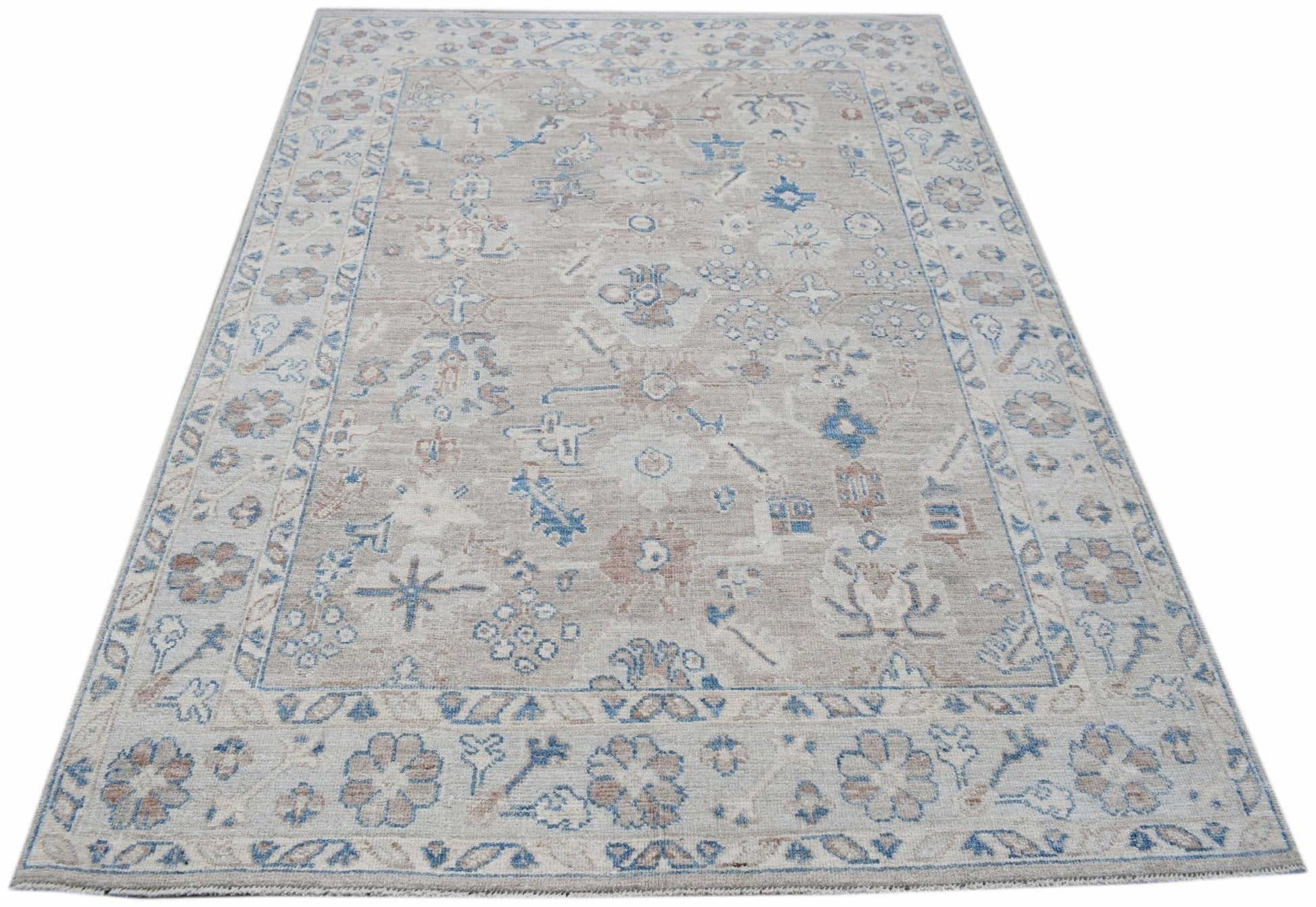 A handwoven transitional Oushak rug featuring a floral pattern in soft blue and beige tones.
