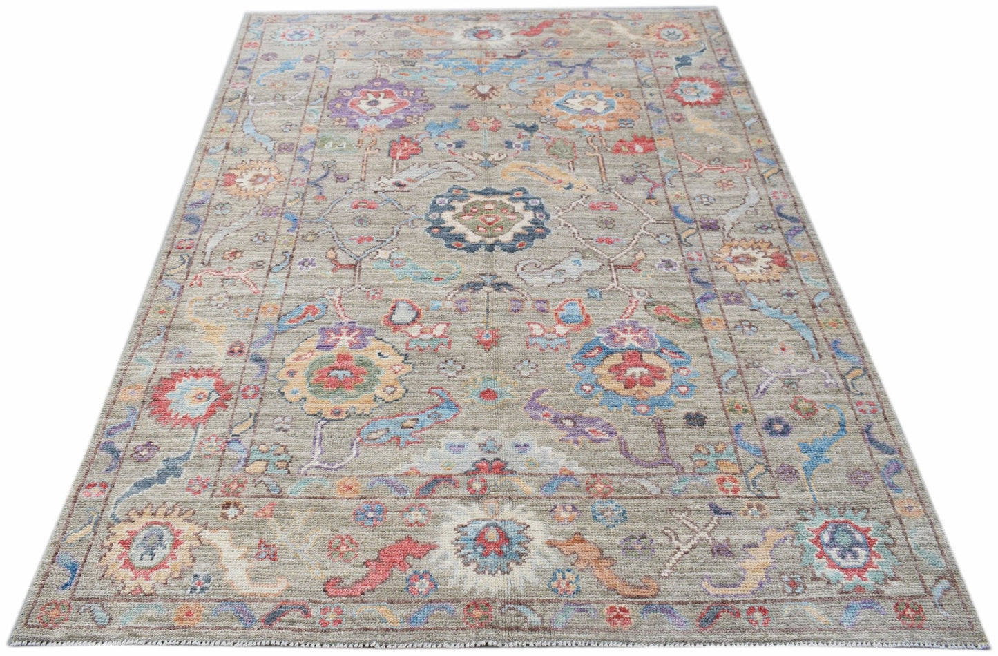A handwoven transitional Oushak rug featuring a floral pattern in muted, multi-colored tones.