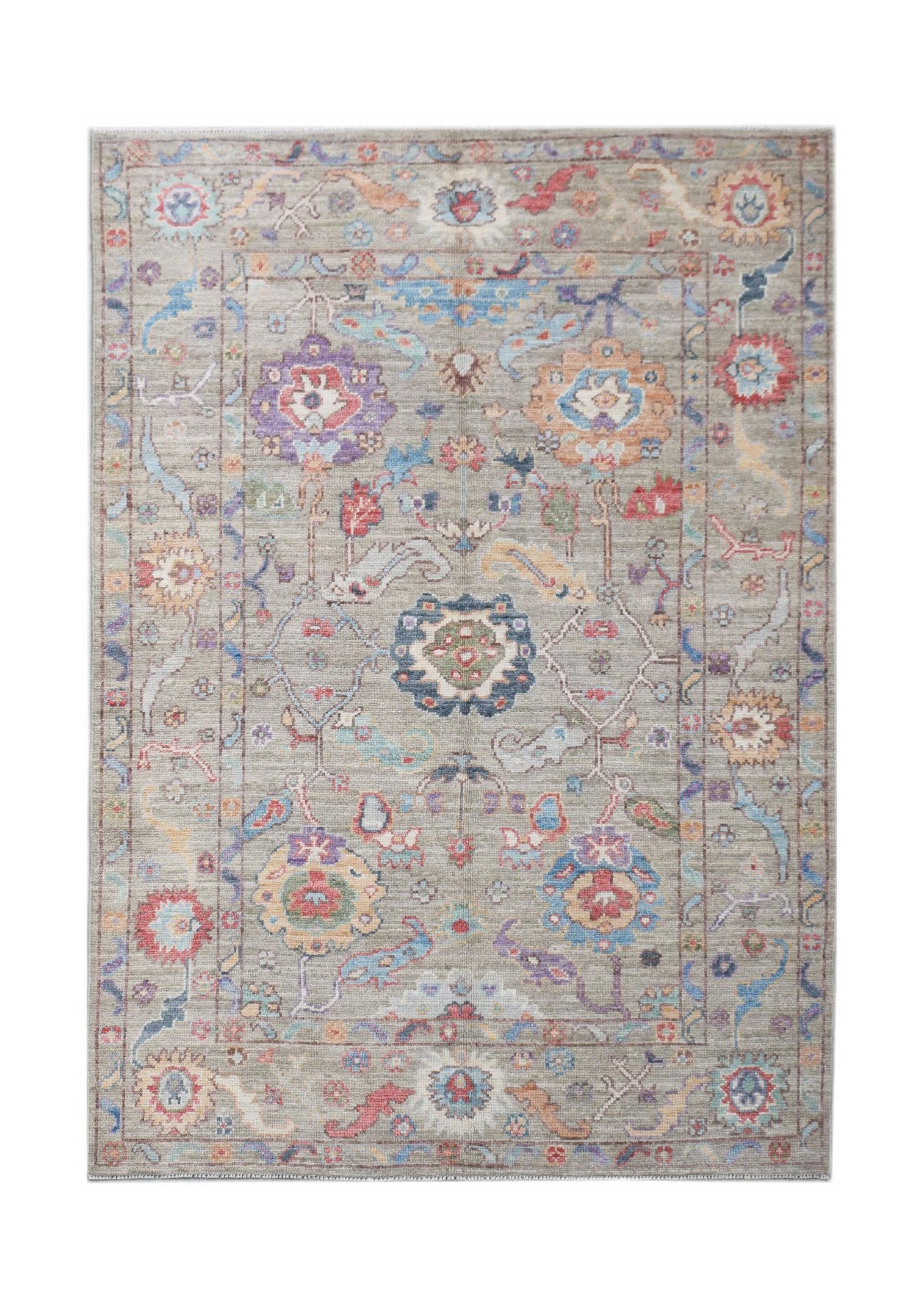 A handwoven transitional Oushak rug featuring a floral pattern in muted, multi-colored tones.