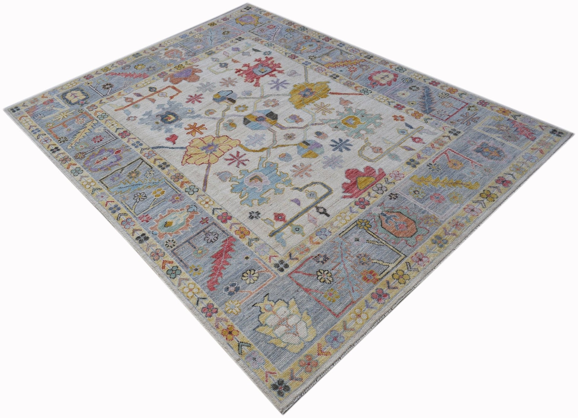 A handwoven transitional Oushak rug featuring a floral pattern in soft blue and muted tones.