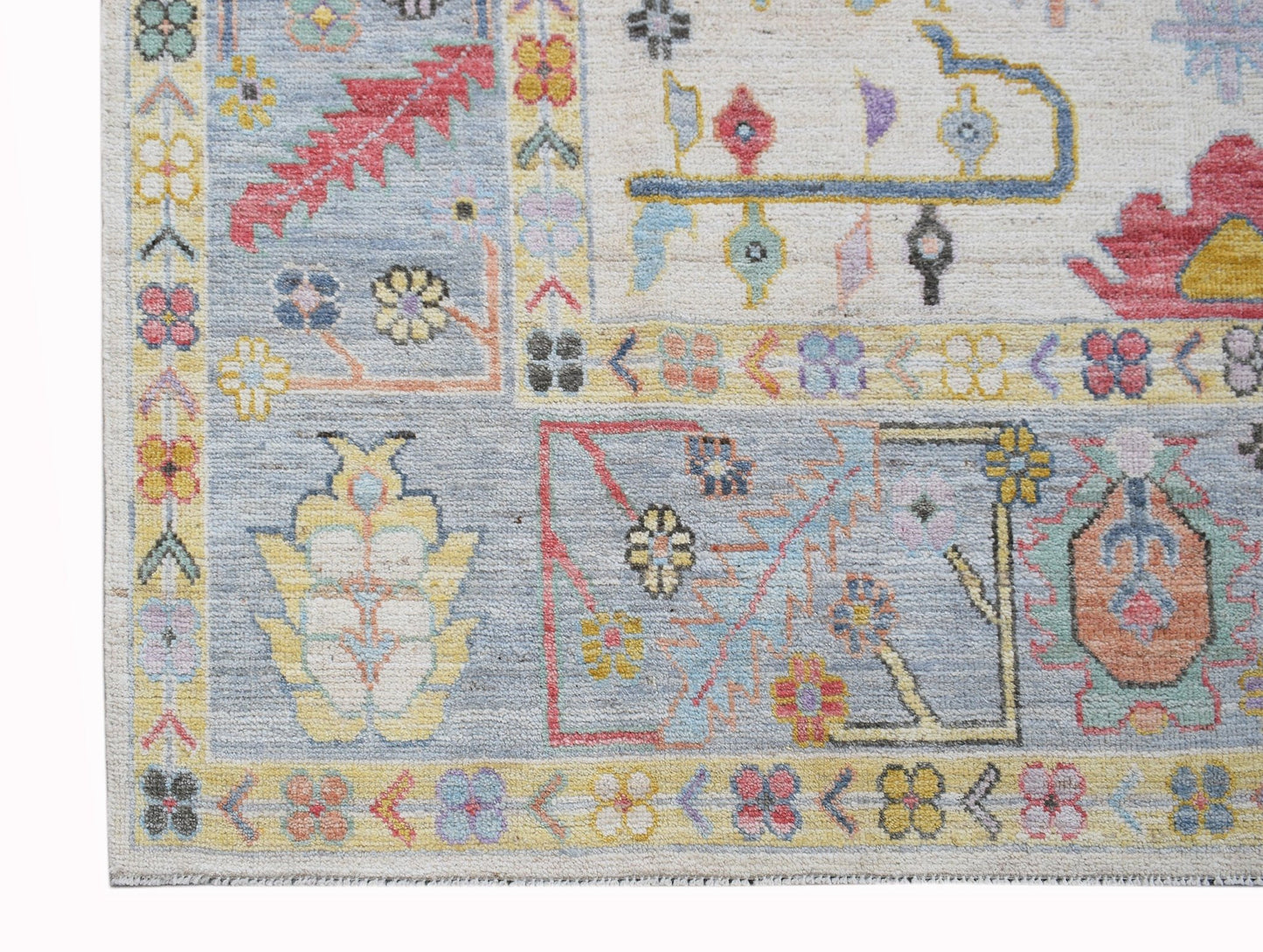 A handwoven transitional Oushak rug featuring a floral pattern in soft blue and neutral tones.