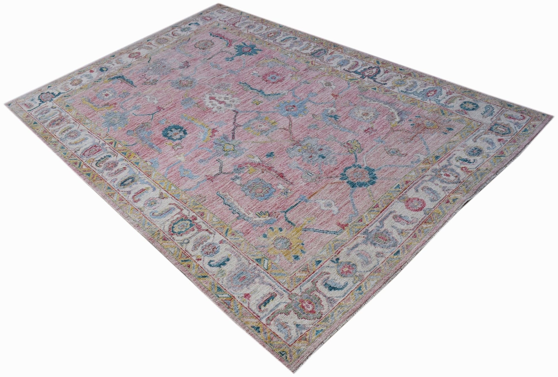 A handwoven transitional Oushak rug featuring a floral pattern in pink, blue, and yellow tones.