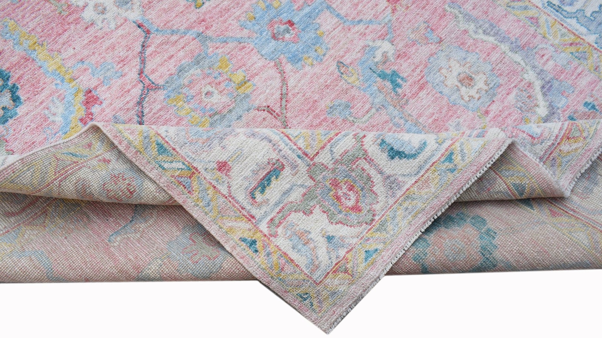 A handwoven transitional Oushak rug featuring a floral pattern in pink, blue, and yellow tones.