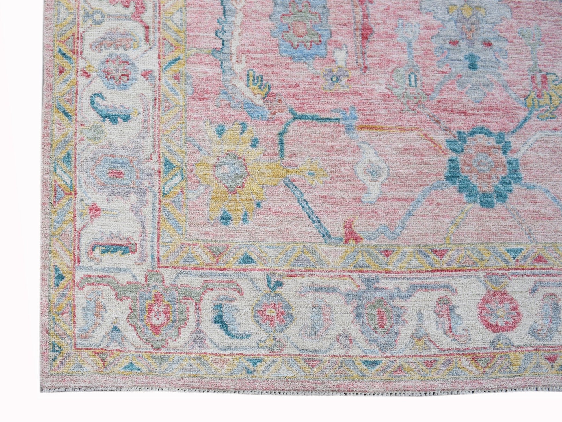 A handwoven transitional Oushak rug featuring a floral pattern in pink, blue, and yellow tones.