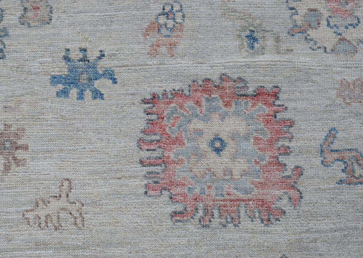 A transitional Oushak rug featuring a light background with scattered floral and geometric motifs.