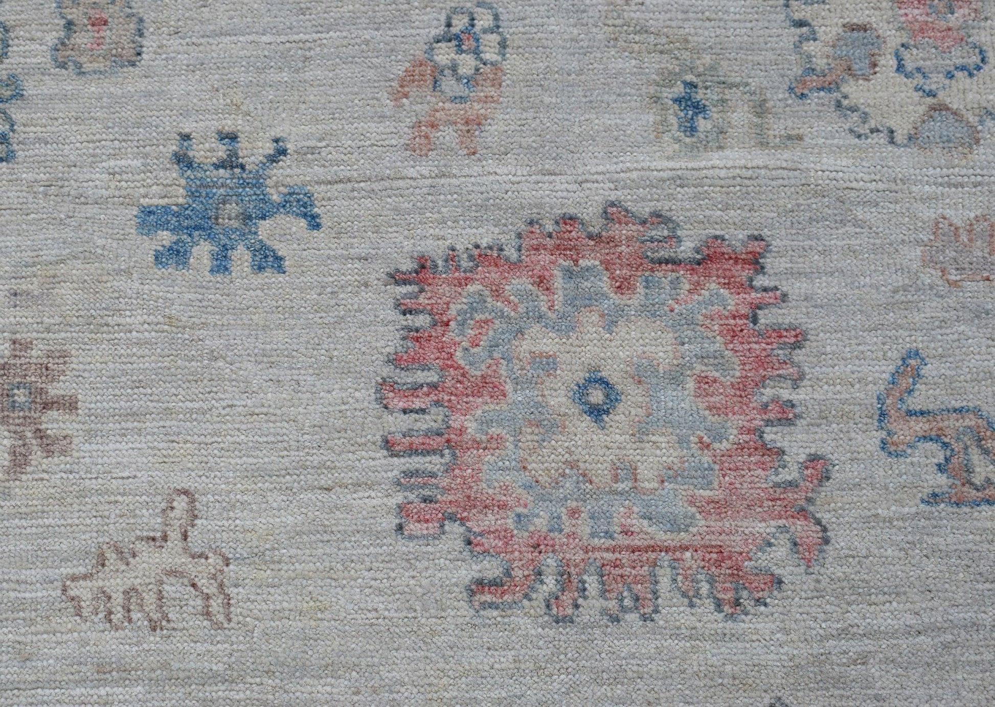 A transitional Oushak rug featuring a light background with scattered floral and geometric motifs.