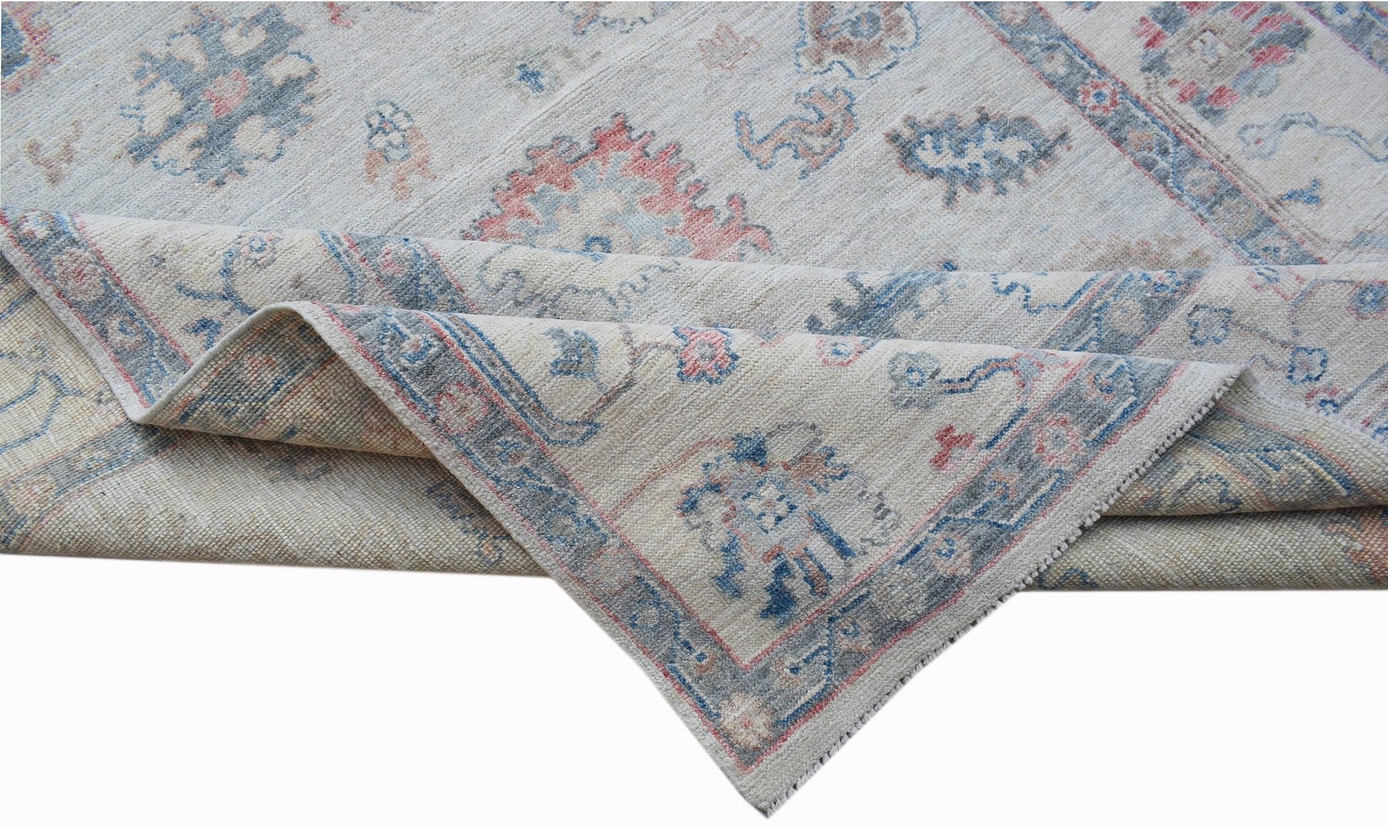 A handwoven transitional Oushak rug featuring a floral pattern in soft blue and pink tones.
