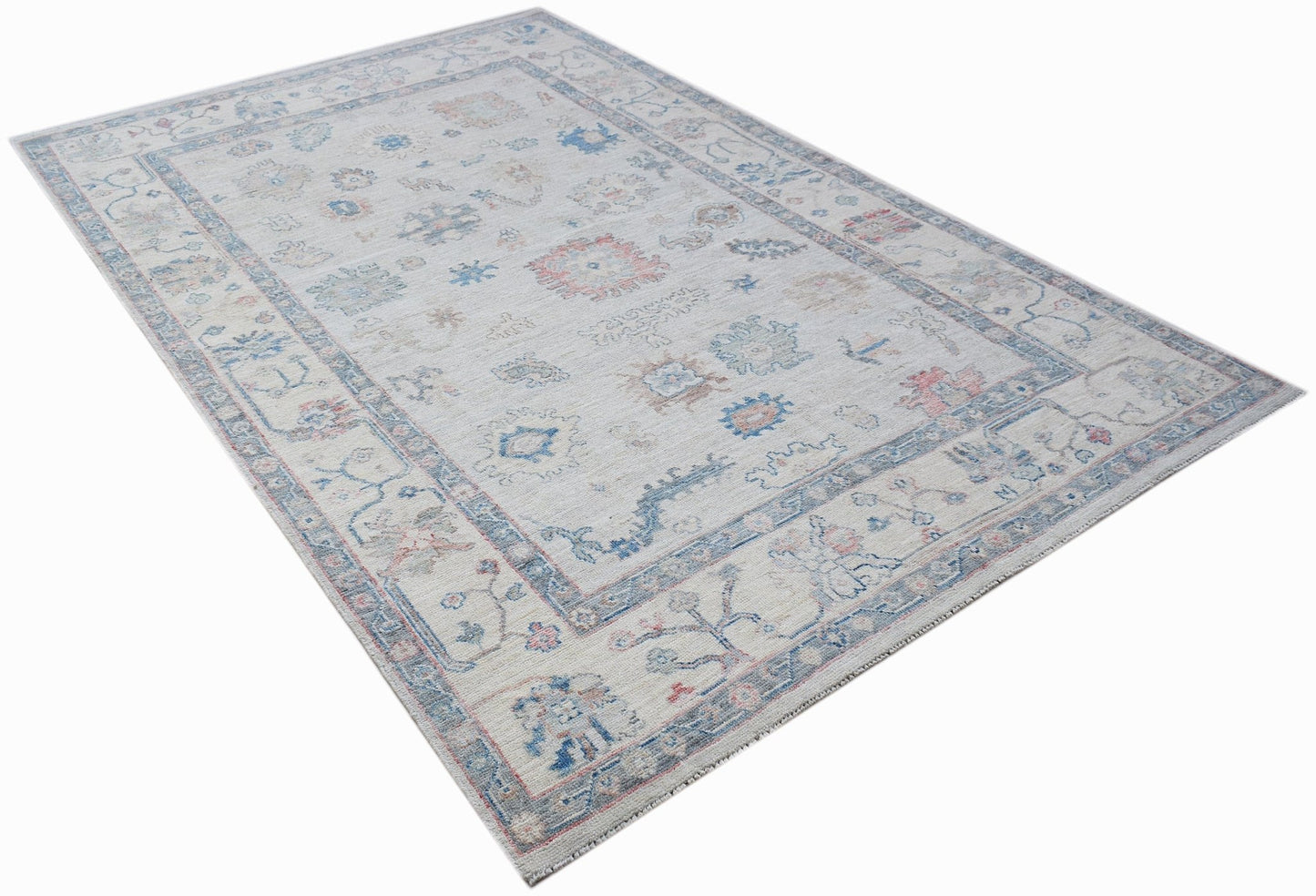 A handwoven transitional Oushak rug featuring a light floral pattern in blue and pink tones.