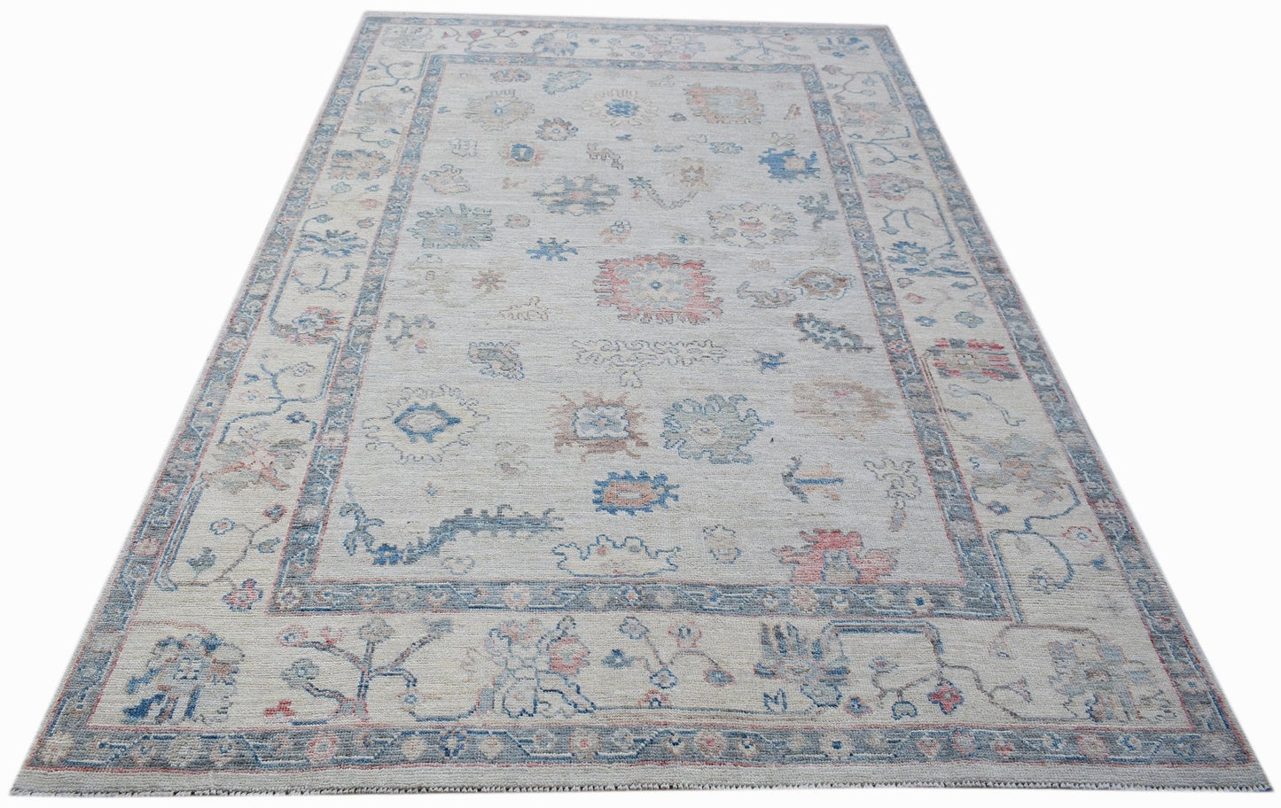 A handwoven transitional Oushak rug featuring a floral pattern in soft blue and pink tones.