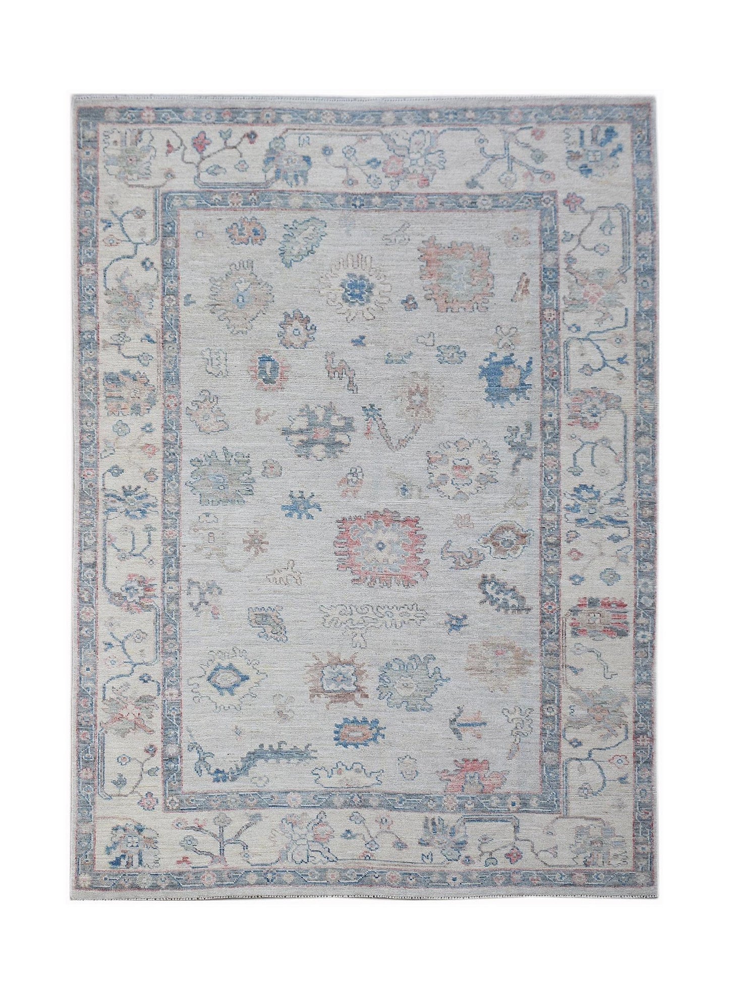 A handwoven transitional Oushak rug featuring a floral pattern in muted blue and pink tones.