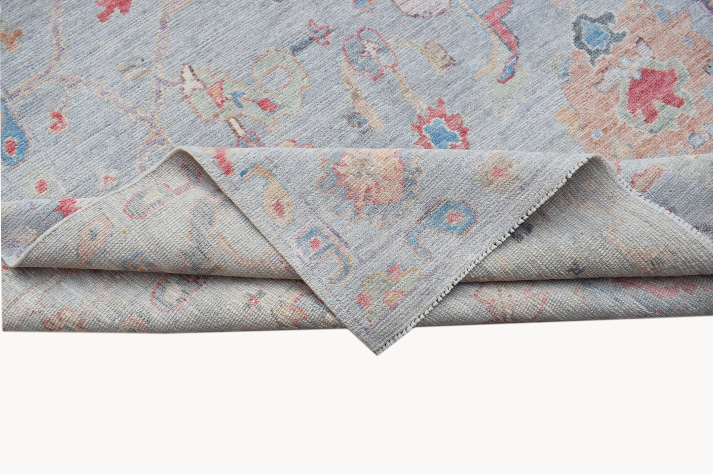 A handwoven transitional Oushak rug featuring a light blue floral pattern on wool.