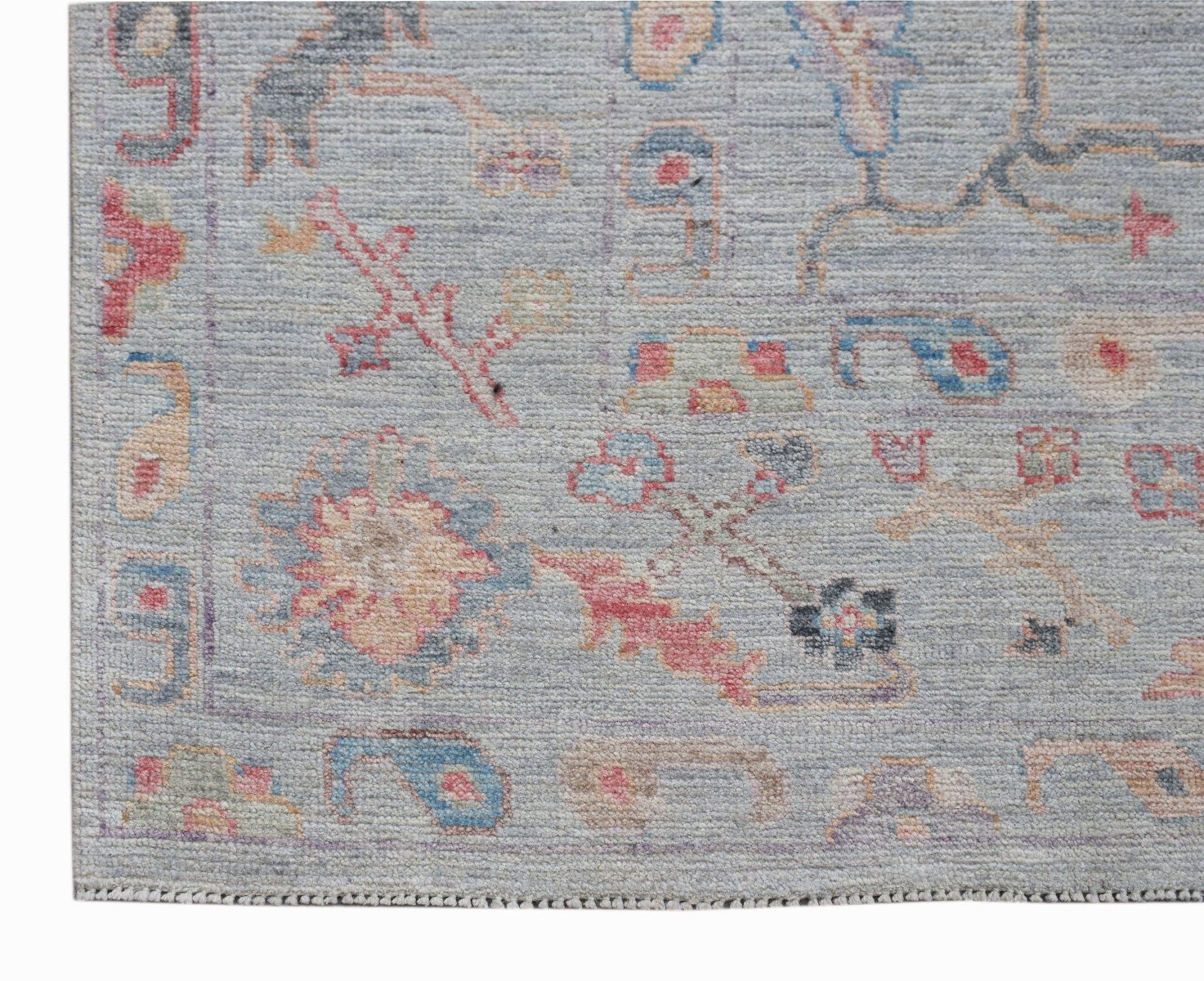 A handwoven transitional Oushak rug featuring a light blue field with colorful floral motifs.