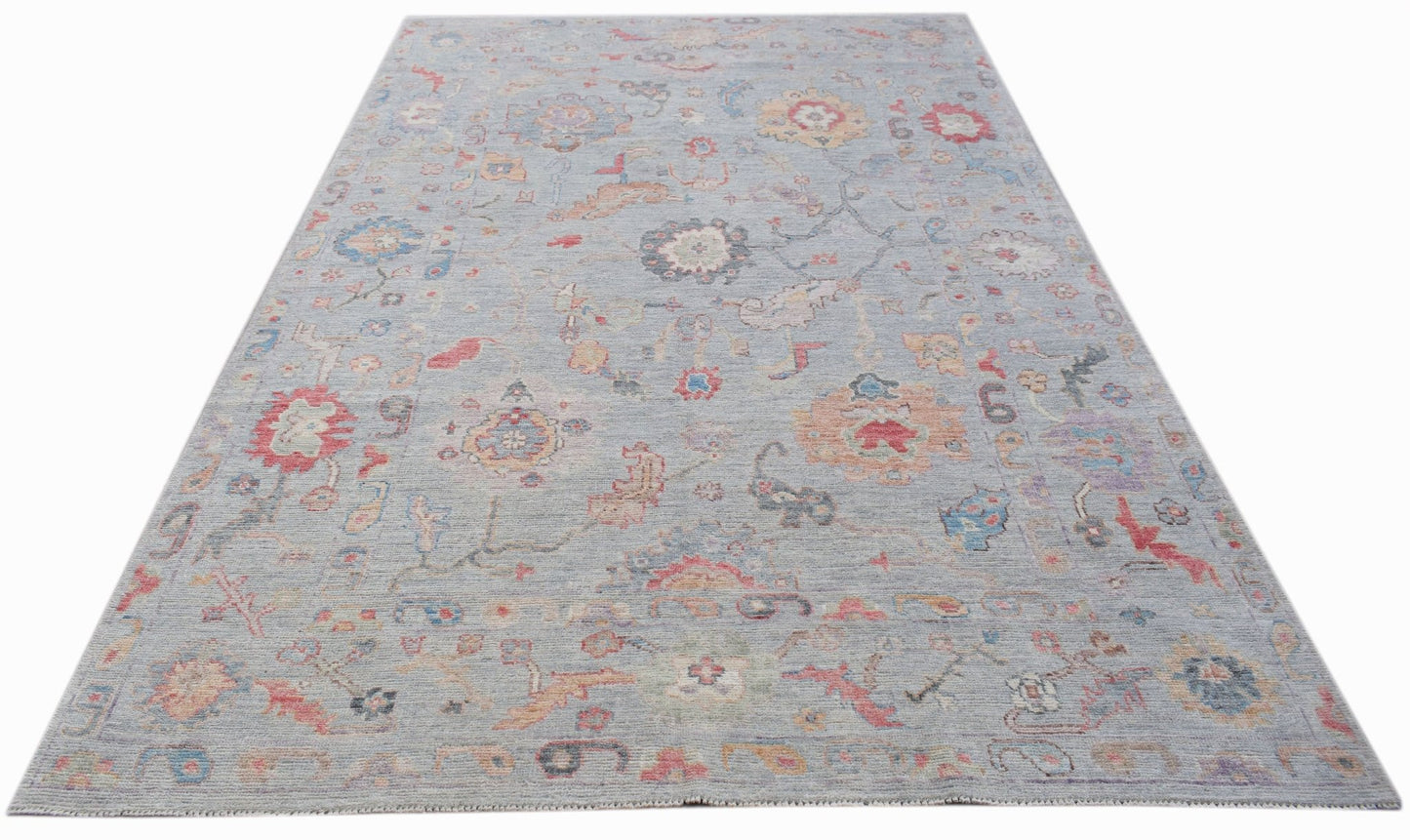 A handwoven transitional Oushak rug featuring a floral pattern in soft, muted colors.