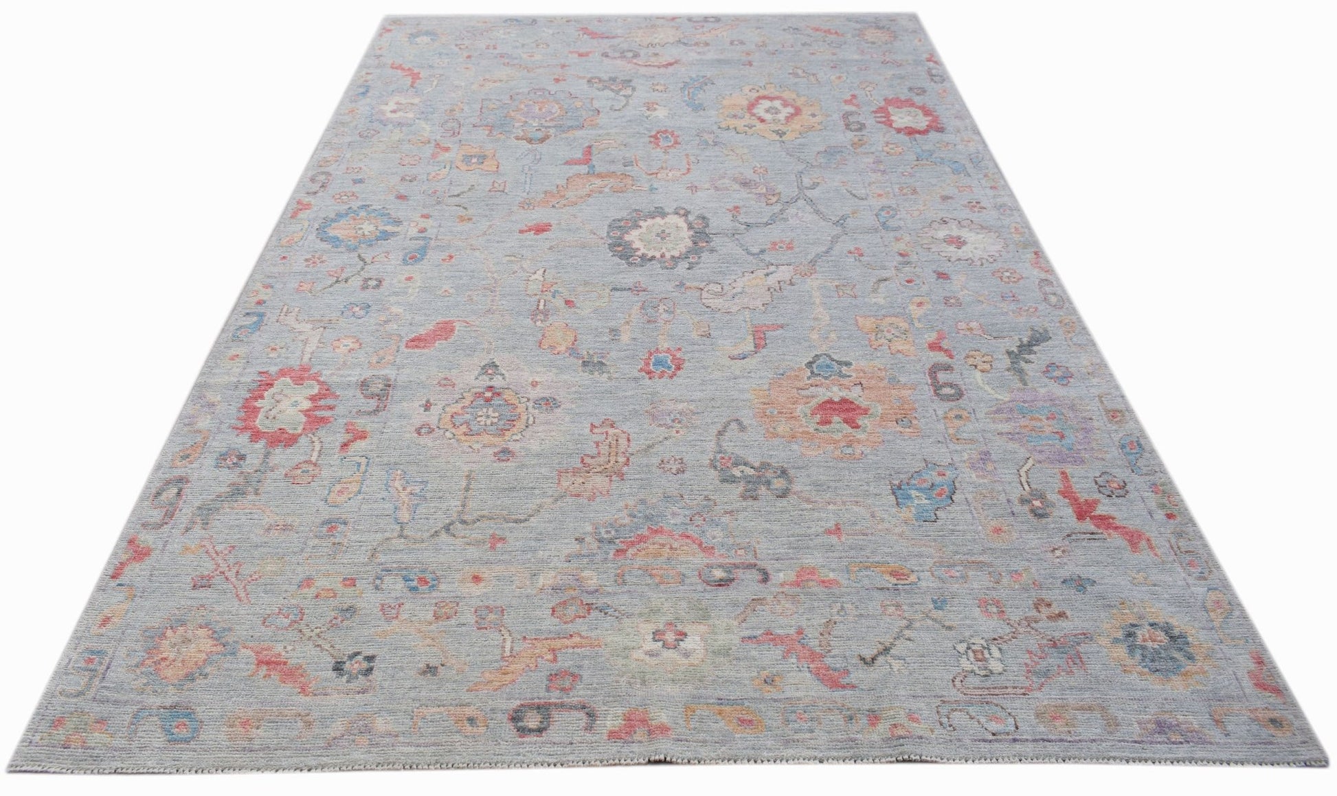 A handwoven transitional Oushak rug featuring a floral pattern in soft, muted colors.