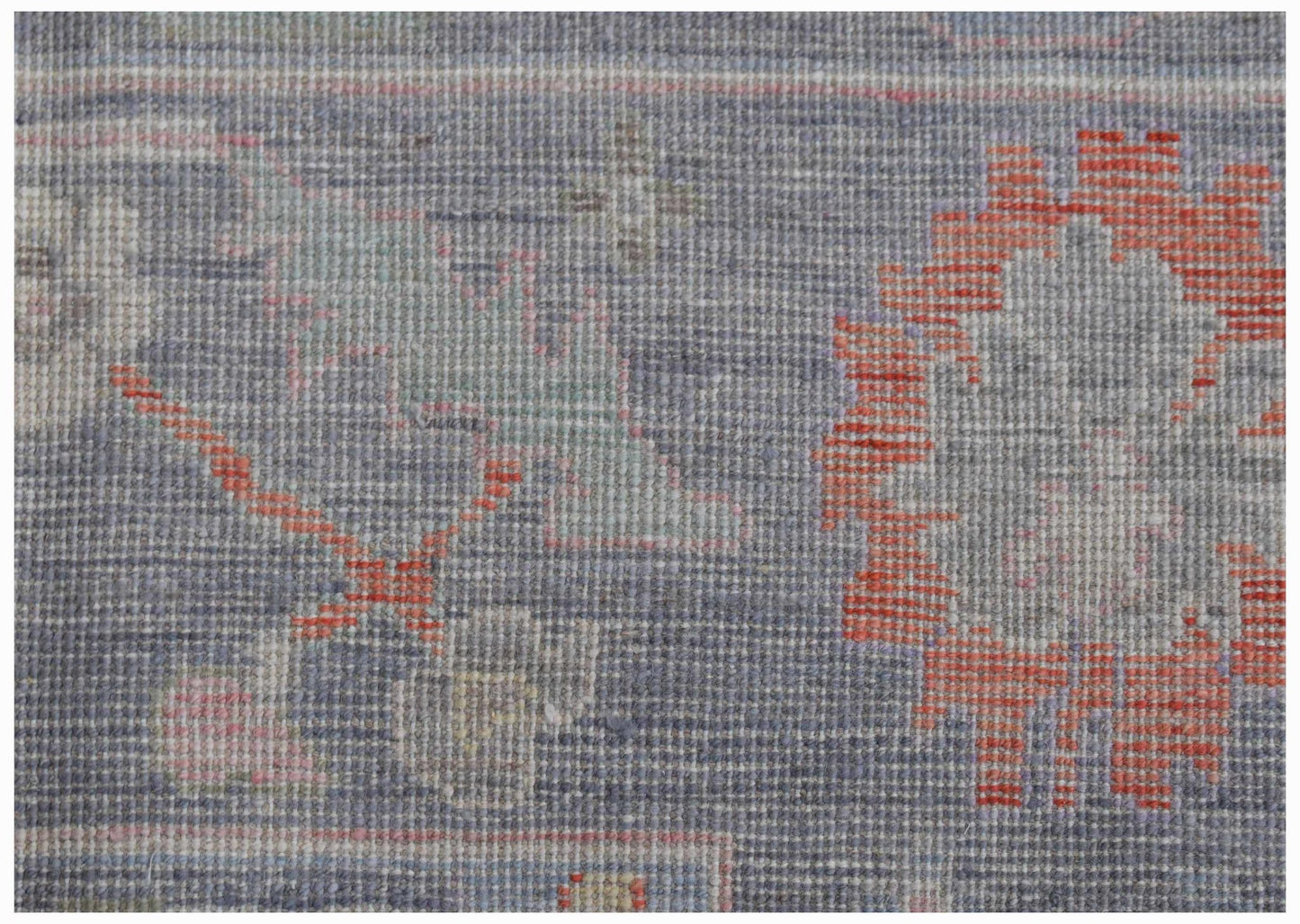 A close-up of a handwoven transitional Oushak rug featuring a floral pattern in blue and orange.