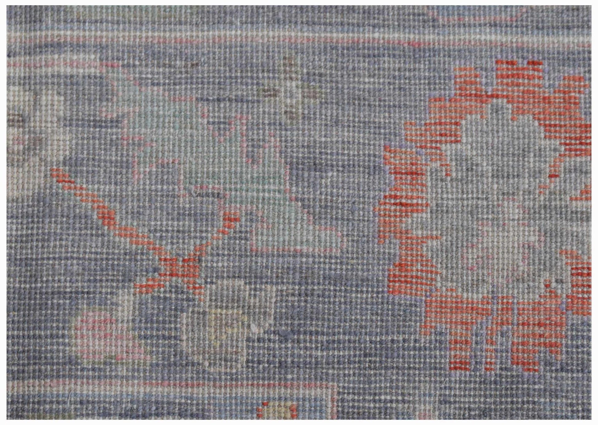 A close-up of a handwoven transitional Oushak rug featuring a floral pattern in blue and orange.