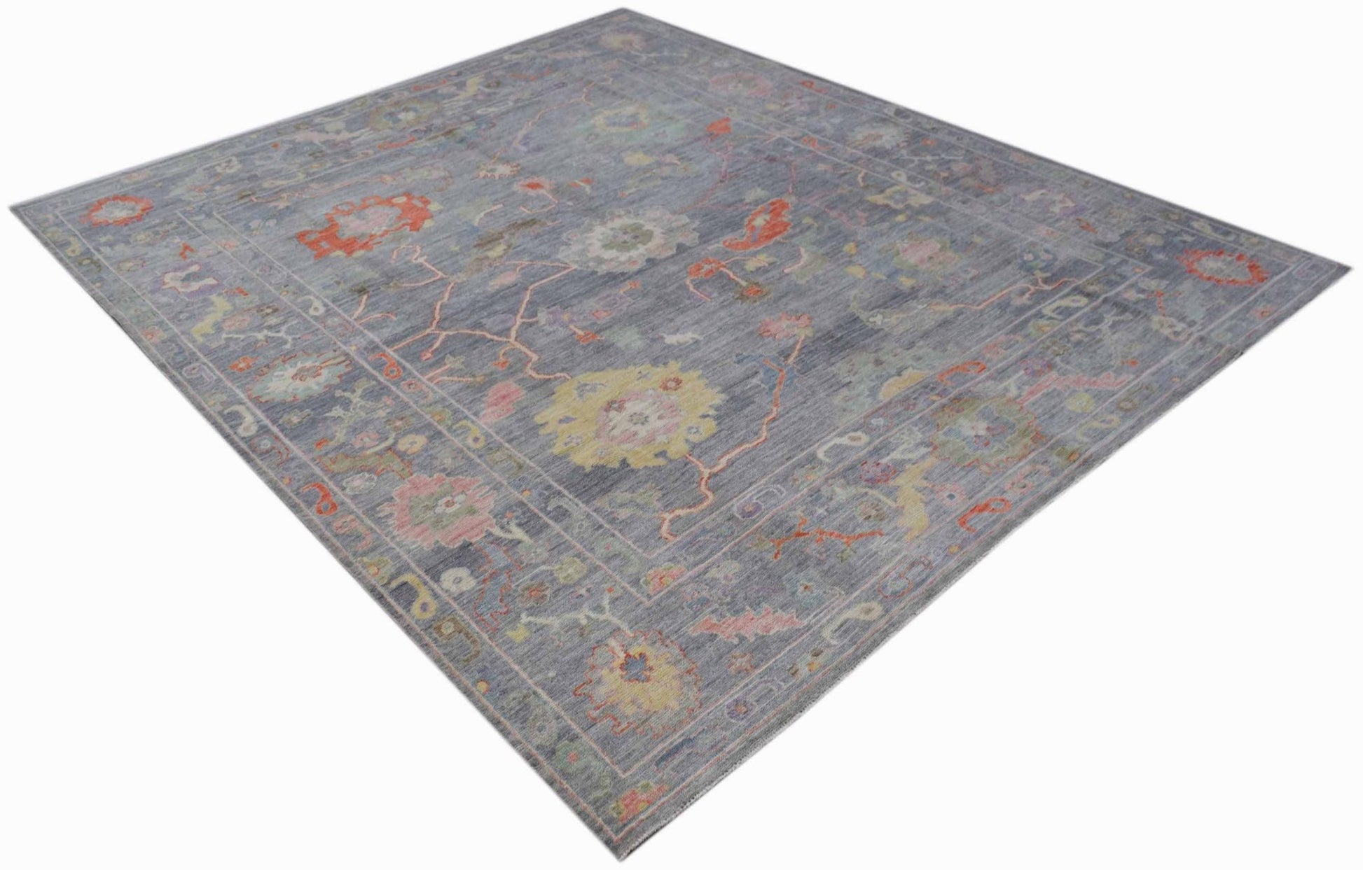 A handwoven transitional Oushak rug featuring a floral pattern in muted tones on a blue background.