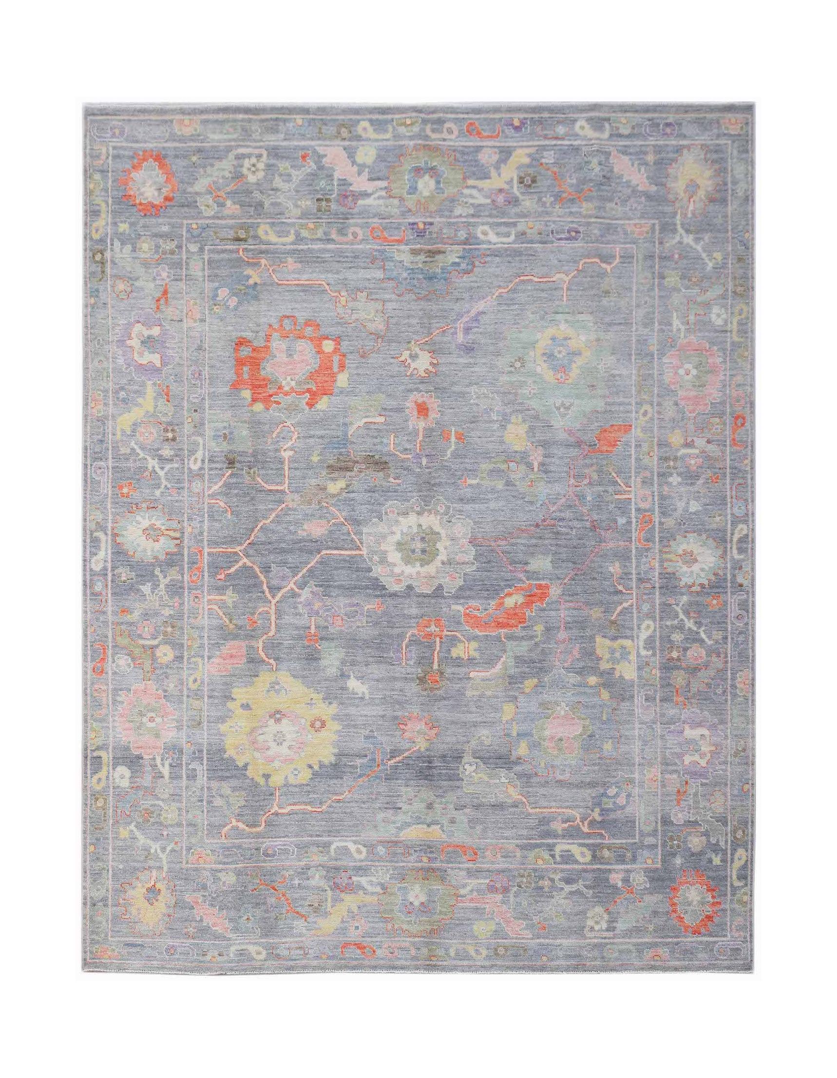 A handwoven transitional Oushak rug featuring a floral pattern in soft colors on a blue background.