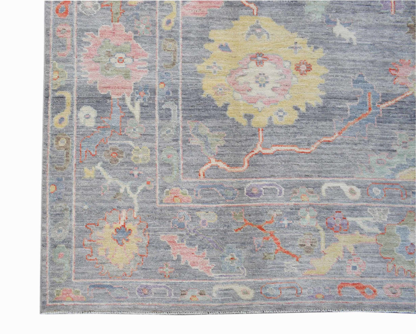 A handwoven transitional Oushak rug featuring a floral pattern in soft pastel tones on a grey base.