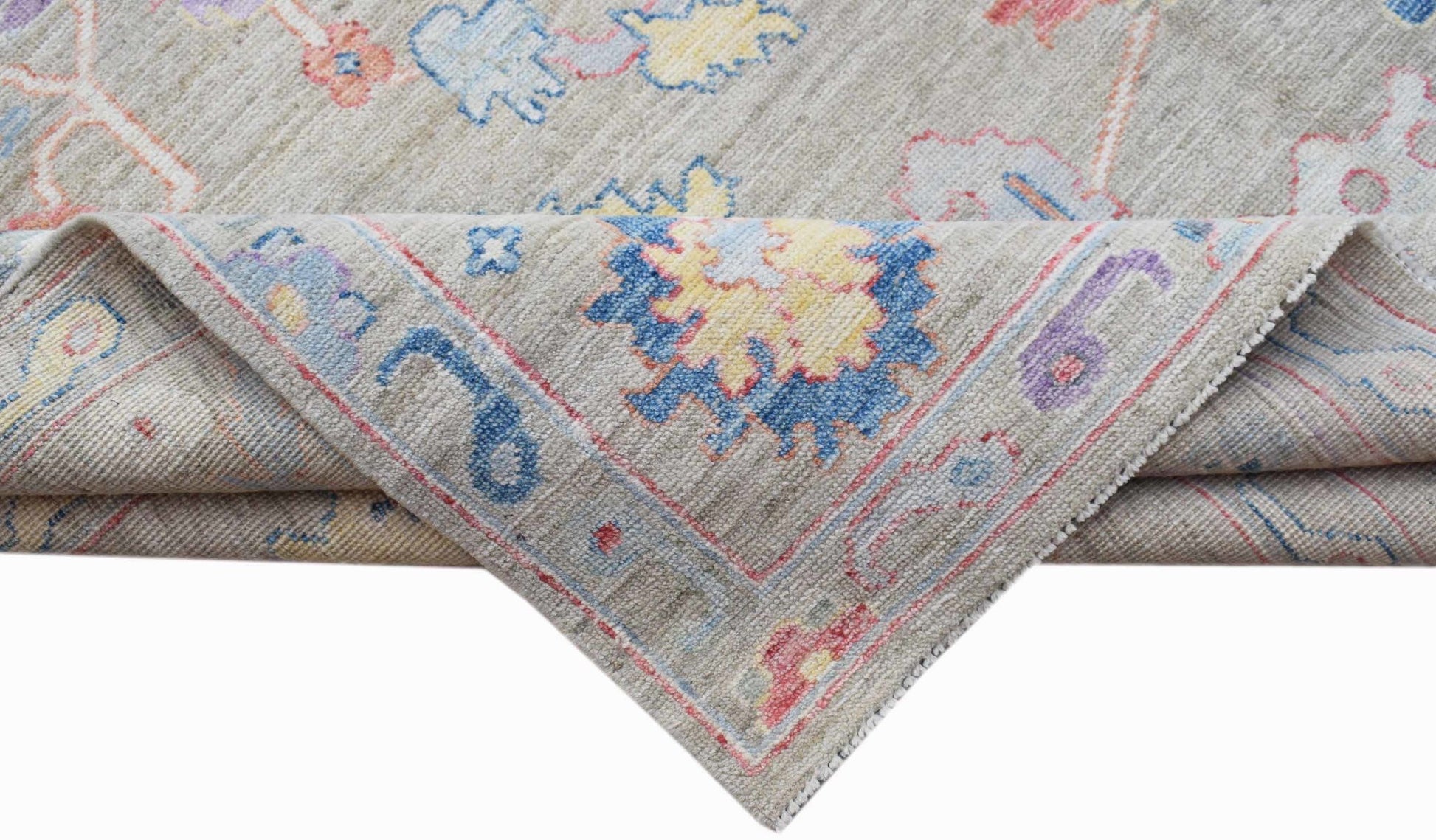 A handwoven transitional Oushak rug with a floral pattern in blue, yellow, and pink on a beige base.