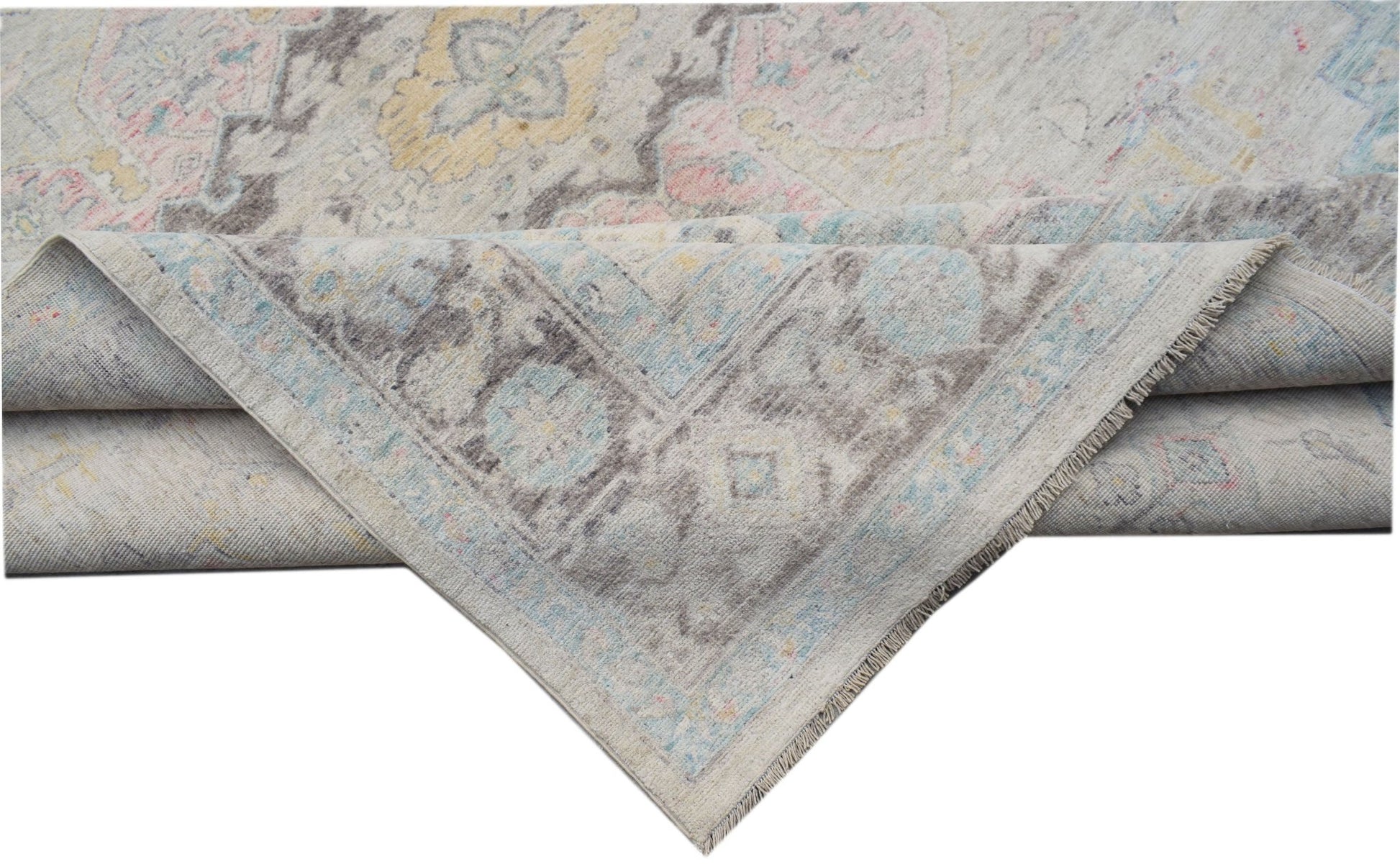 A handwoven transitional Oushak rug featuring a floral pattern in soft pastel and grey tones.