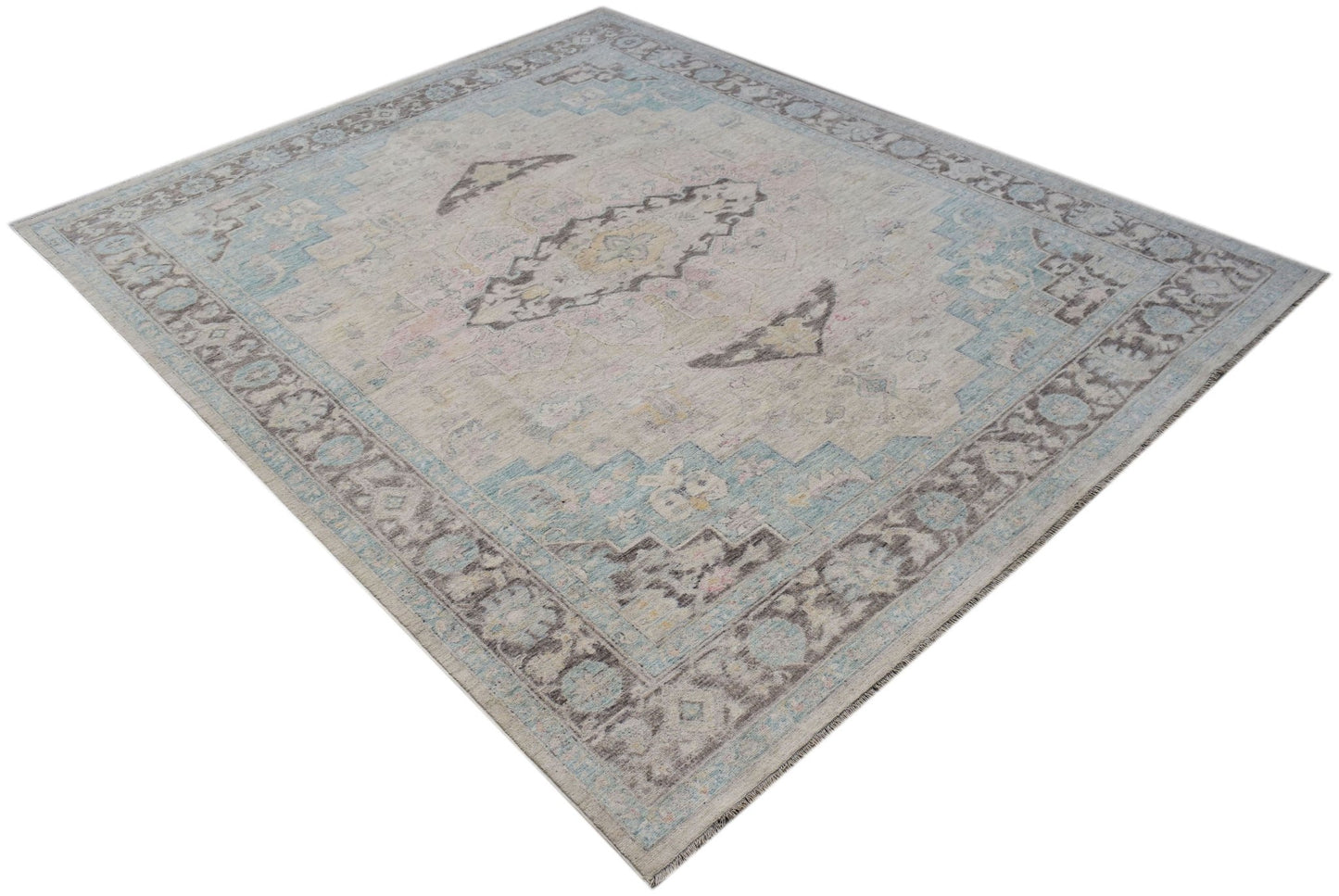 A handwoven transitional Oushak rug featuring a light grey, blue, and beige floral pattern.