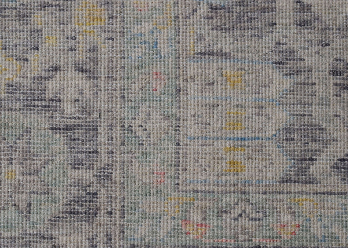 A handwoven transitional Oushak rug featuring a distressed pattern in grey, yellow, and blue tones.